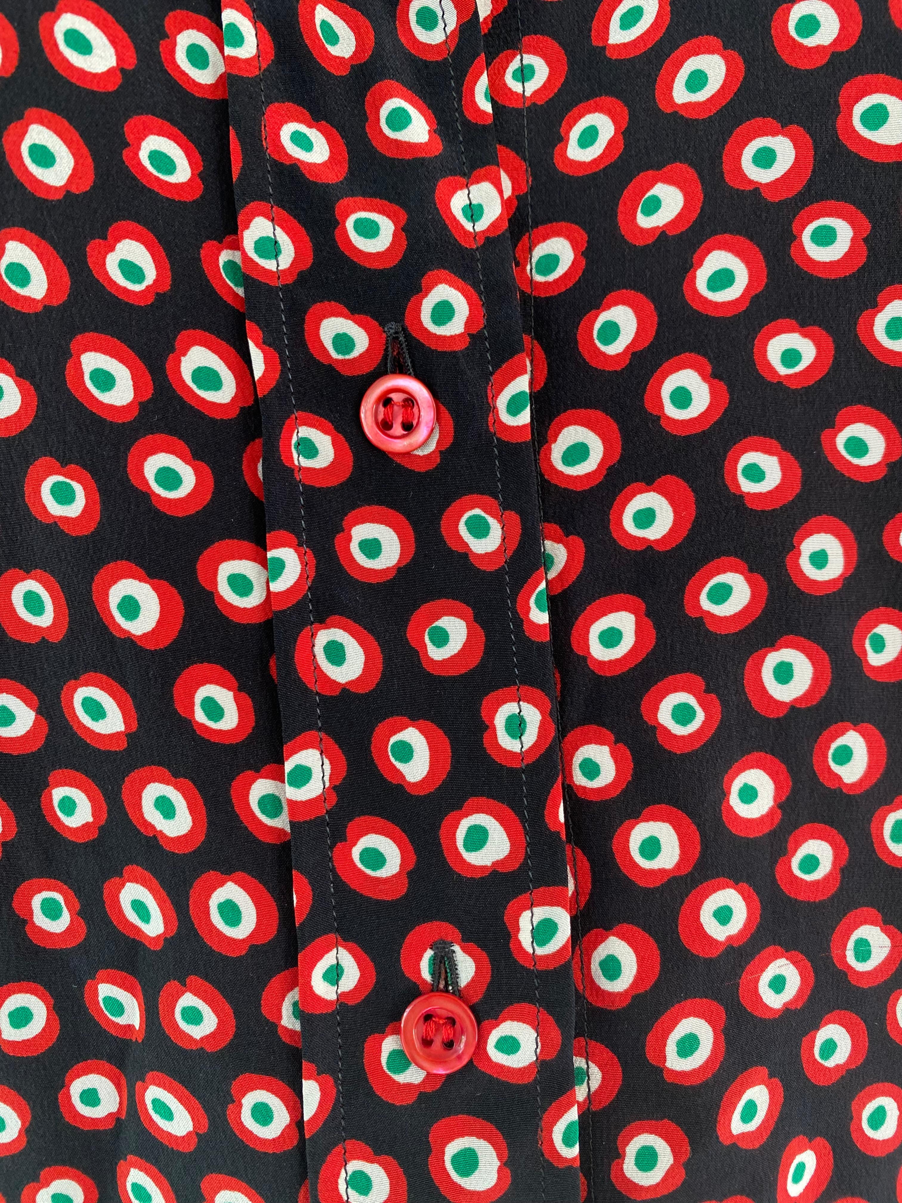 1970s YSL Yves Saint Laurent Rive Gauche red patterned button down shirt. To fabric tag but it feels like a silk. The buttons are red and it has a bow from the same fabric that can be tied around the neck. The circular pattern is set on a black