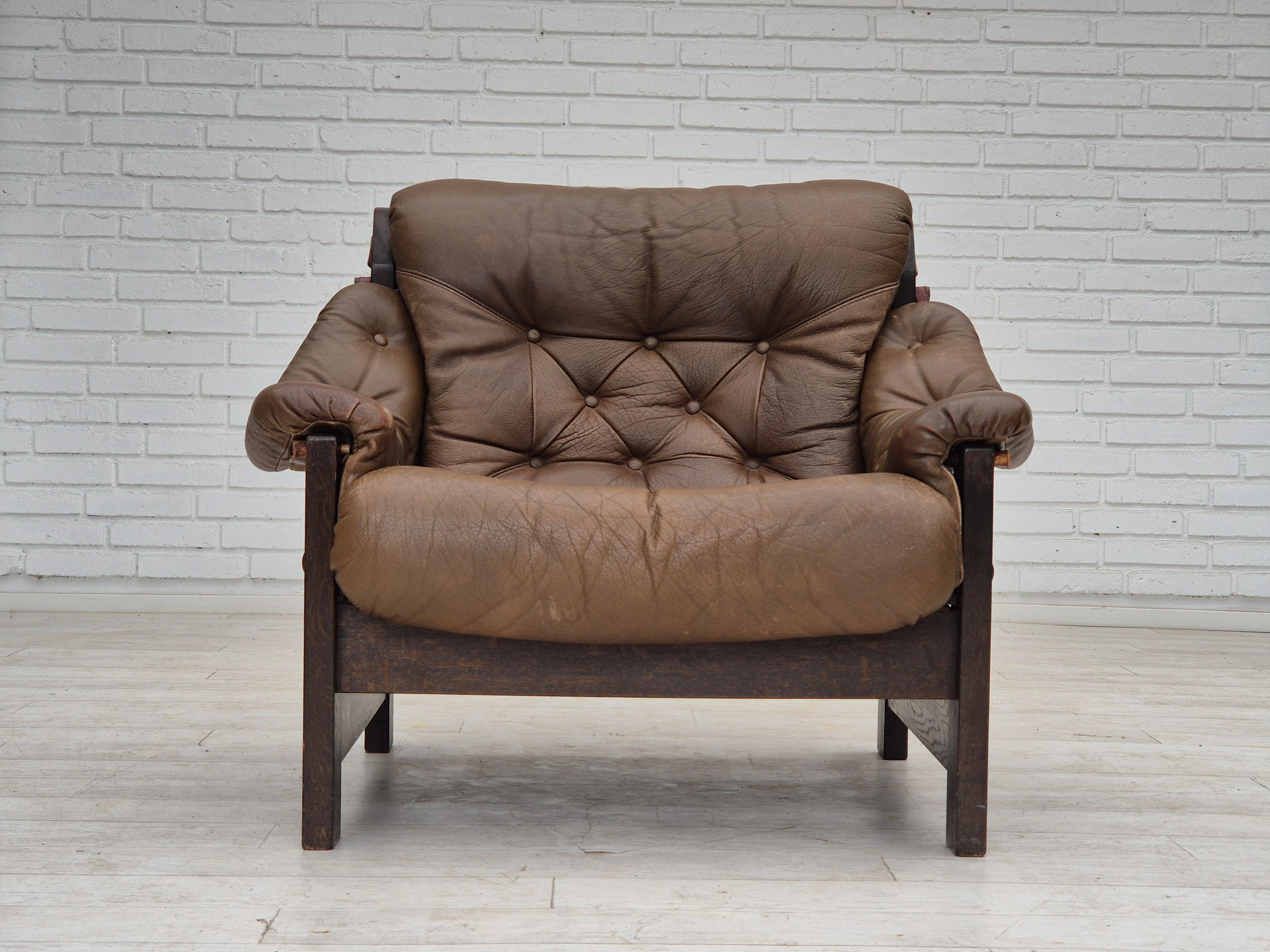 Années 1970, Design/One. Chaise de style safari, d'origine en très bon état : pas d'odeurs ni de taches. Construction originale en cuir marron, toile marron et bois de chêne. Bretelles en cuir avec fermoirs en laiton. Fabriqué par un fabricant de