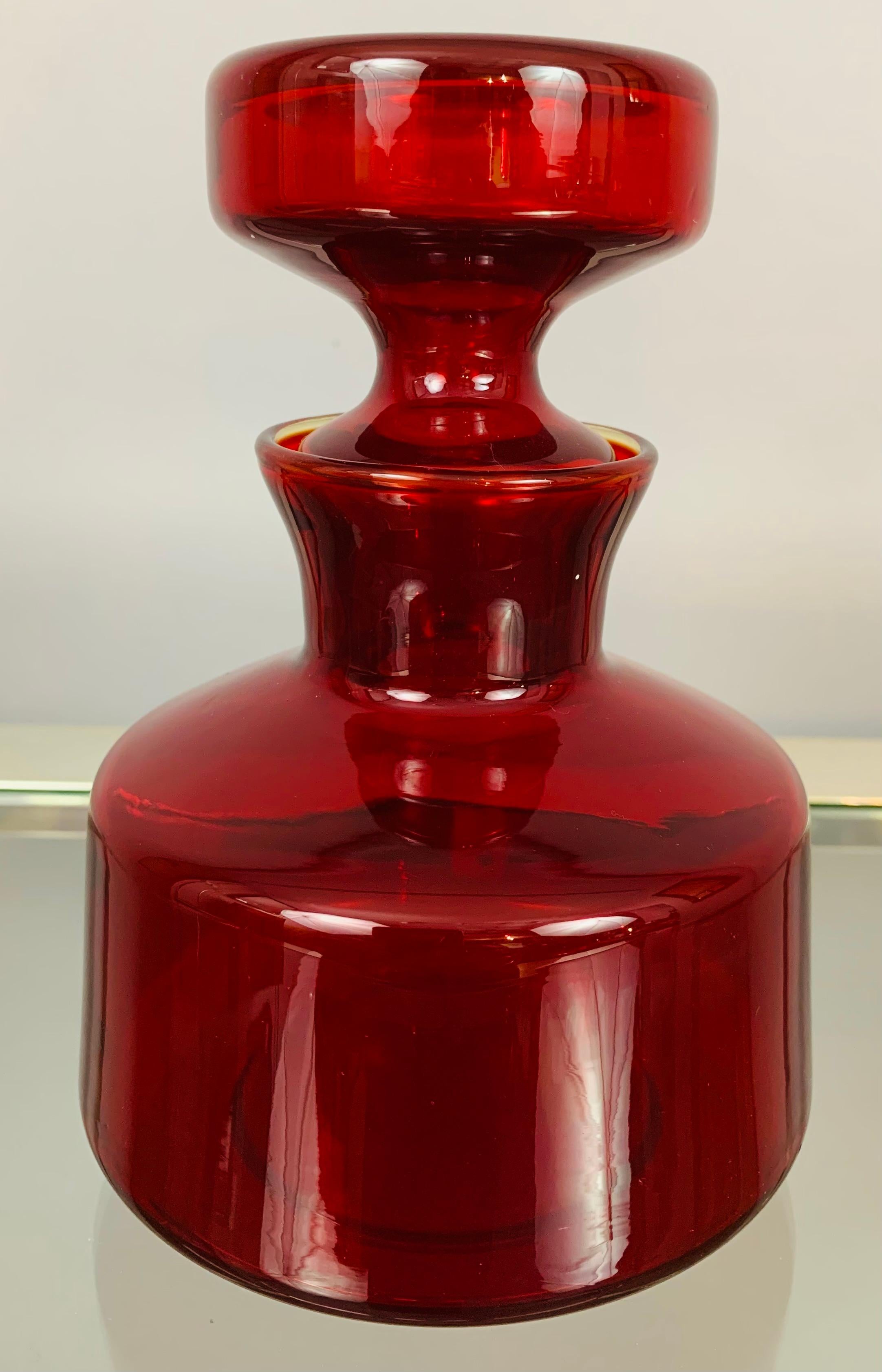 1960s Ruby red glass flask with a decorative stopper in the style of Finnish glassmaker Riihimaki and designer Tamara Aladin. A well-made and functional piece. Beautifully designed and a perfect addition to any glass collection to add some colour