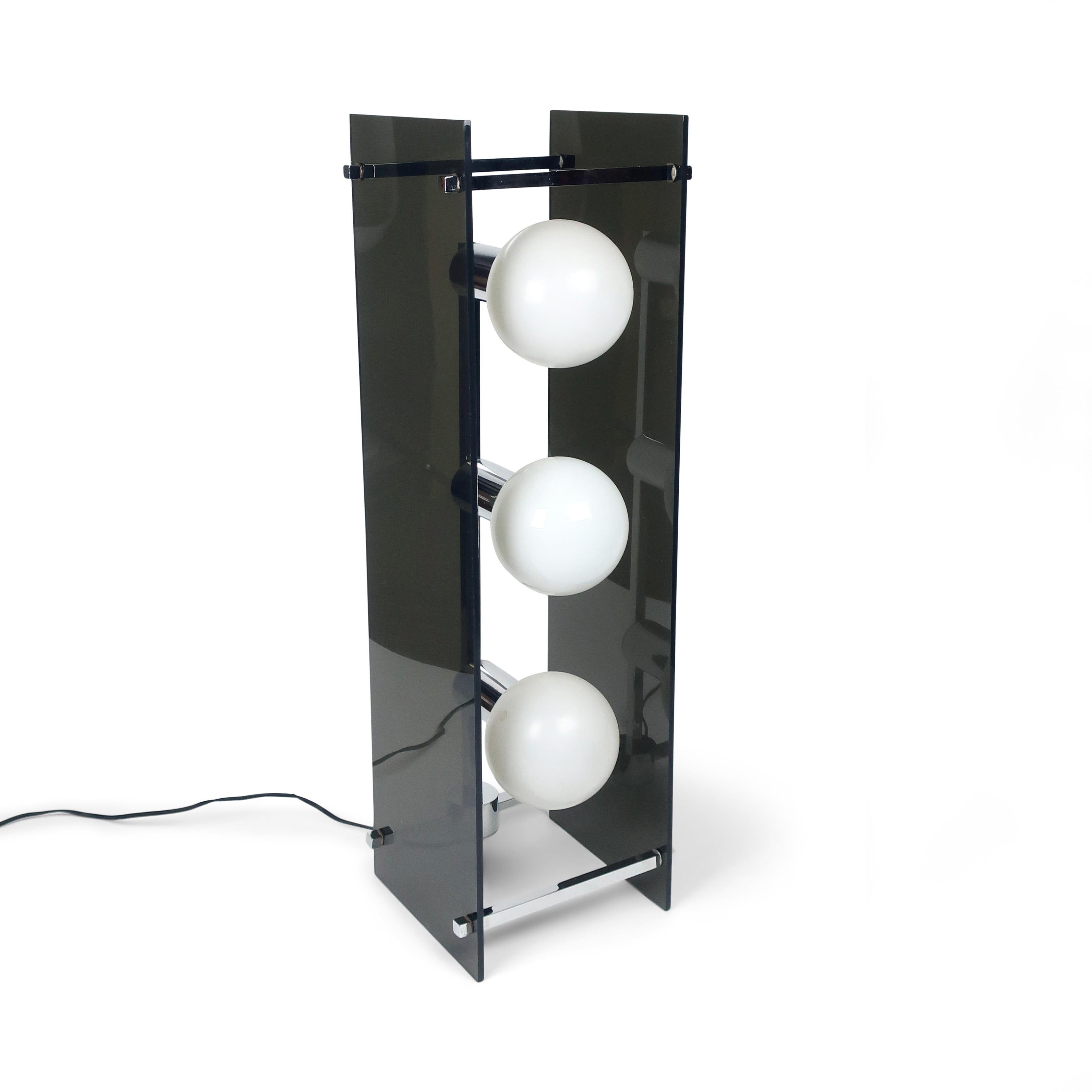 A seductive and sophisticated mid-century modern sculptural table lamp in chrome and dark gray smoked lucite. Suspended between two large rectangular pieces of lucite and connected with chrome accents, this three globe bulb lamps has a 3 way switch
