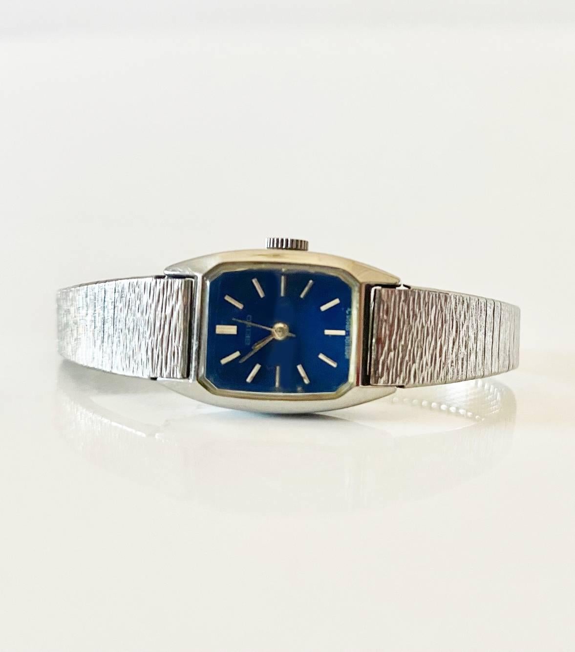 Diese elegante und kultige Seiko Jewell Edelstahluhr aus den 1970er Jahren mit blauem Zifferblatt verfügt über ein manuelles Uhrwerk, eine analoge Anzeige, ein 12-Stunden-Zifferblatt, Mineralglas und eine Krone mit Druck-/Zugmechanismus, alles mit