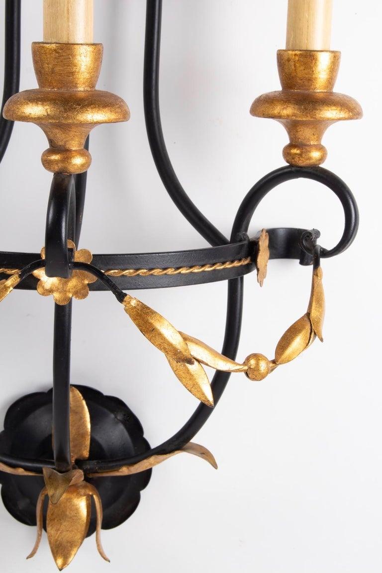 Composed of a black wrought iron structure in the shape of a semicircle positioned in the center of the wall lamp on which is placed 3 black wrought iron rods forming ascending and descending volutes.
It is embellished with a pretty decoration of a