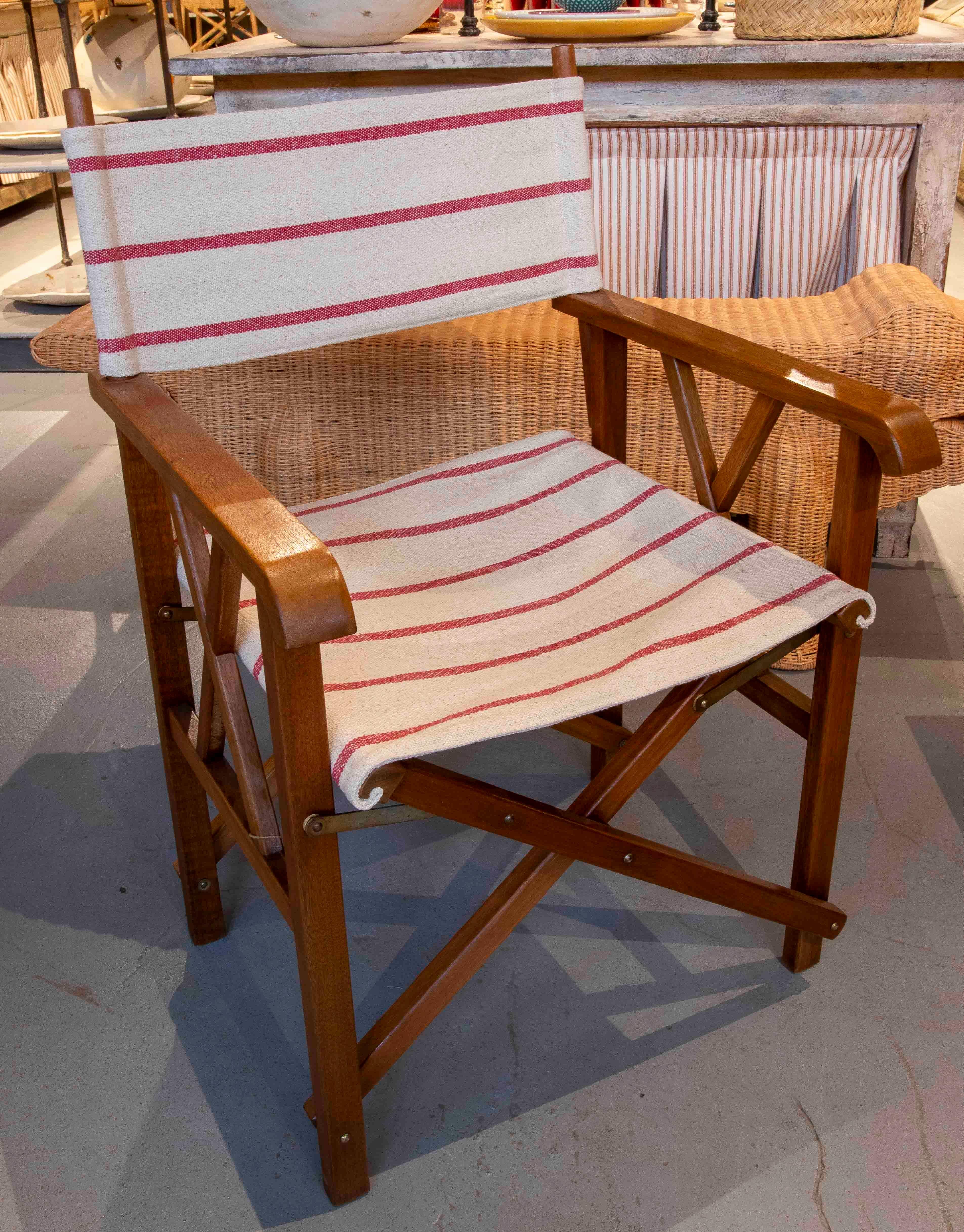 Set of four vintage-style director's chairs, crafted from wood with a warm, natural tone and featuring durable canvas seats and backs in a classic red-striped design on a natural background. Their lightweight, foldable frame maintains the