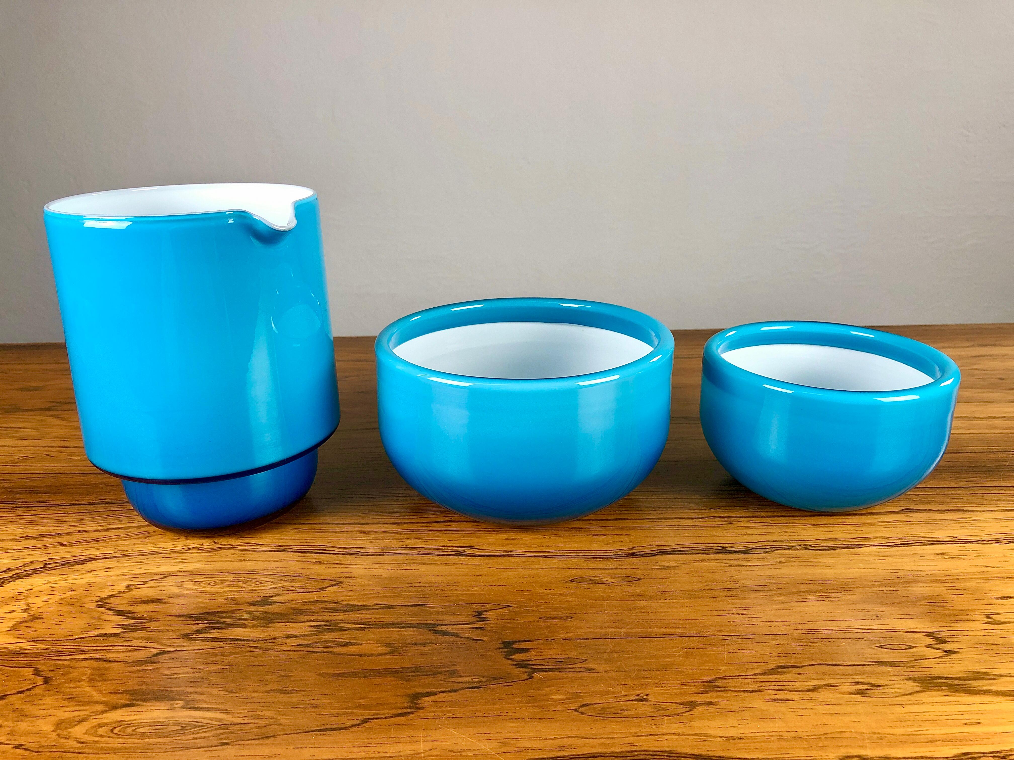 Set of two bowls and a pitcher in blue hand blown opal glass, designed by Michael Bang and produced by Holmegaard in the 1970s.

The well designed set with it´s 1970´s colors is in very good condition.

Michael Bang (1942-2013) was the son of