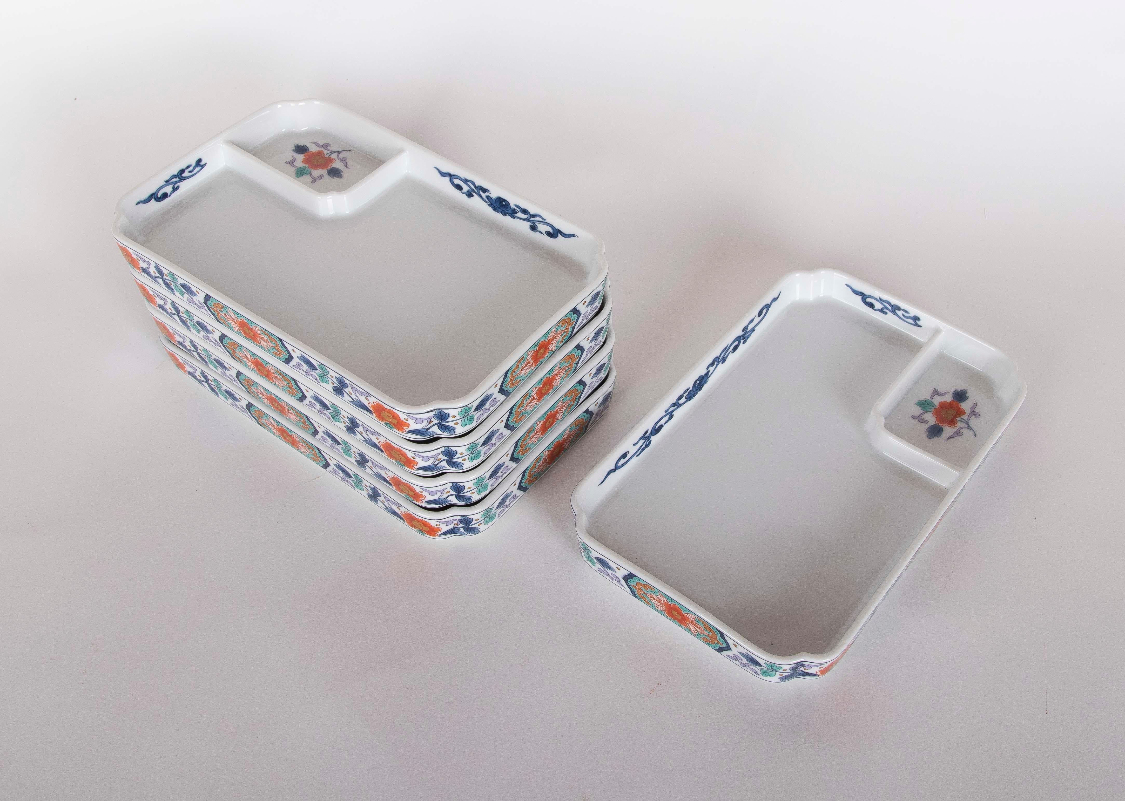 Ensemble d'assiettes rectangulaires en porcelaine décorées de motifs floraux dans des tons vifs de rouge, bleu et vert, associés à des motifs géométriques sur les bords. Chaque assiette dispose d'un compartiment supplémentaire, idéal pour séparer