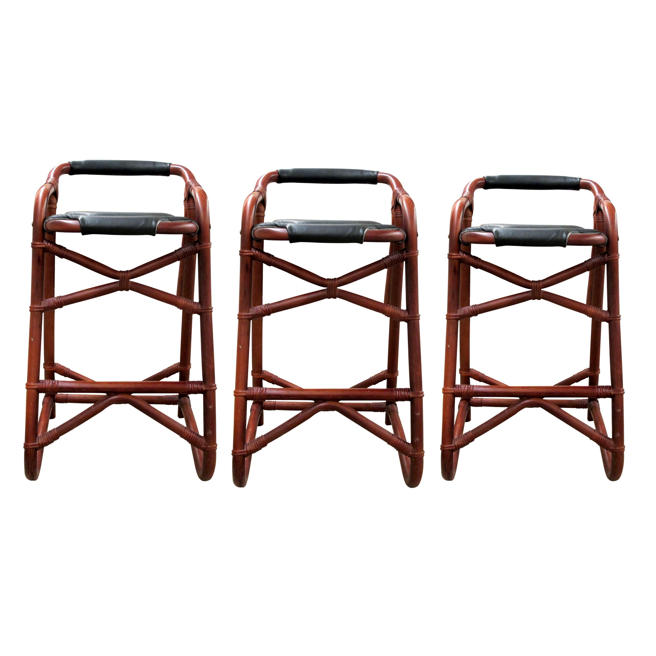 1970s set of three French Riviera bar stools with a sturdy bamboo frame. The stools are upholstered with black leather, the seat pads are padded for extra comfort. The bamboo frames are very well made, and the joinery is made with ratan.   

Size: