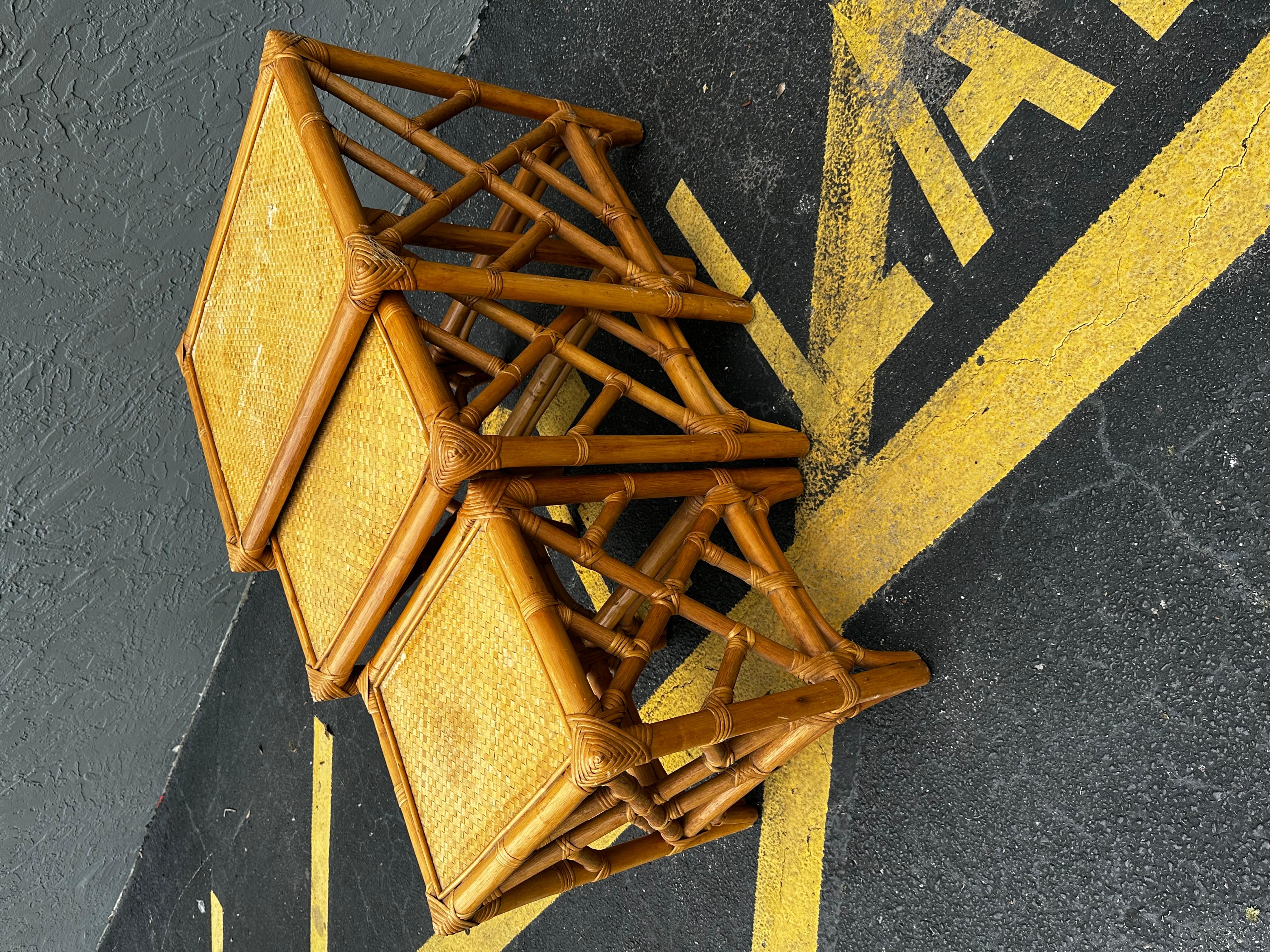 Handsome nest of three rattan side tables featuring a raffia grasscloth inset on the top.
Made by McGuire in the California organic modern style. Constructed from rattan poles lashed together with leather laces on the exposed joints.