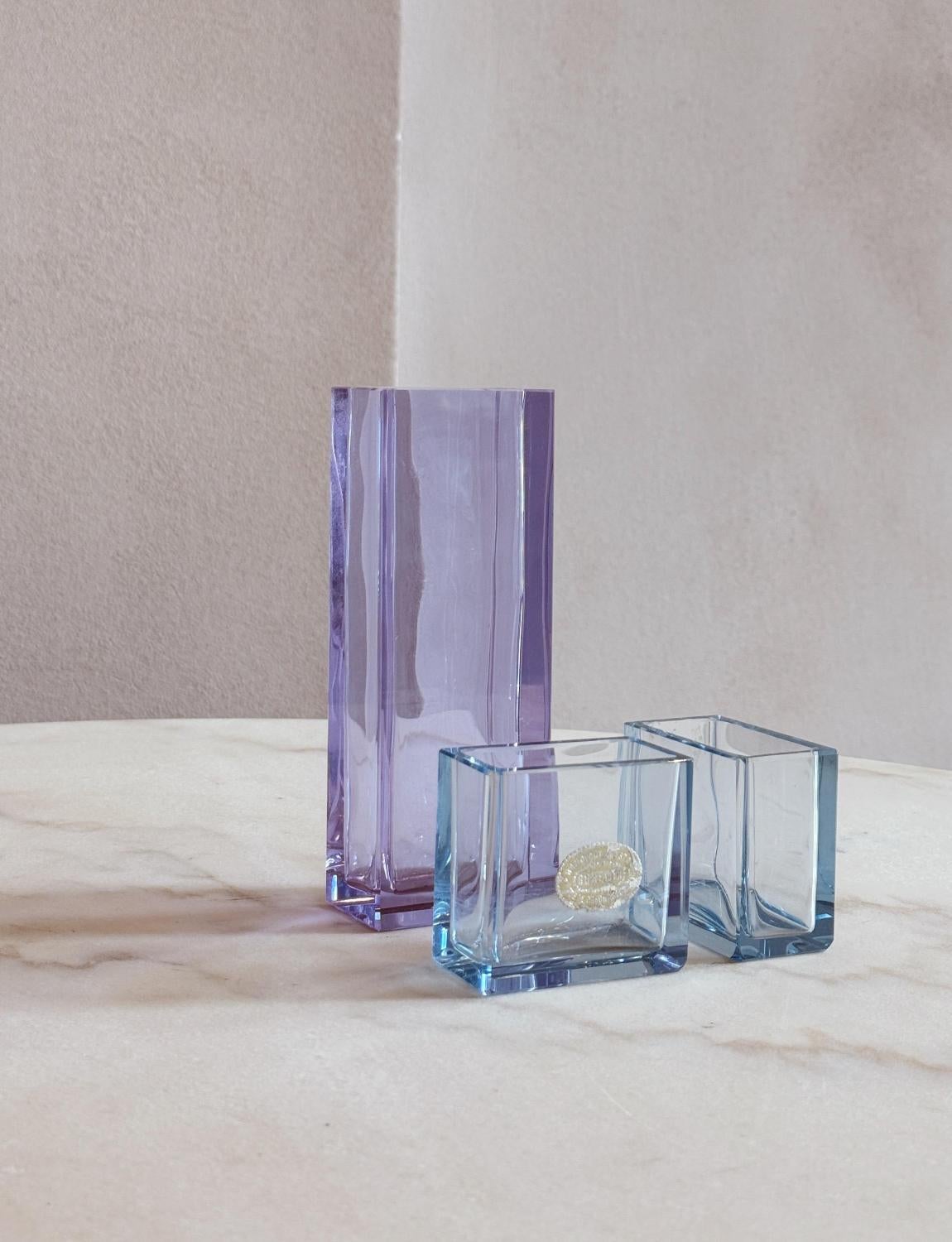 Ein entzückendes Set von Miniaturvasen aus den 1970er Jahren. Die größte Vase ist fliederfarben und die beiden kleineren sind aus hellblauem Glas mit noch vorhandenem Originalaufkleber. Alles in gutem Zustand.

Abmessungen: Fliederfarbene Vase: