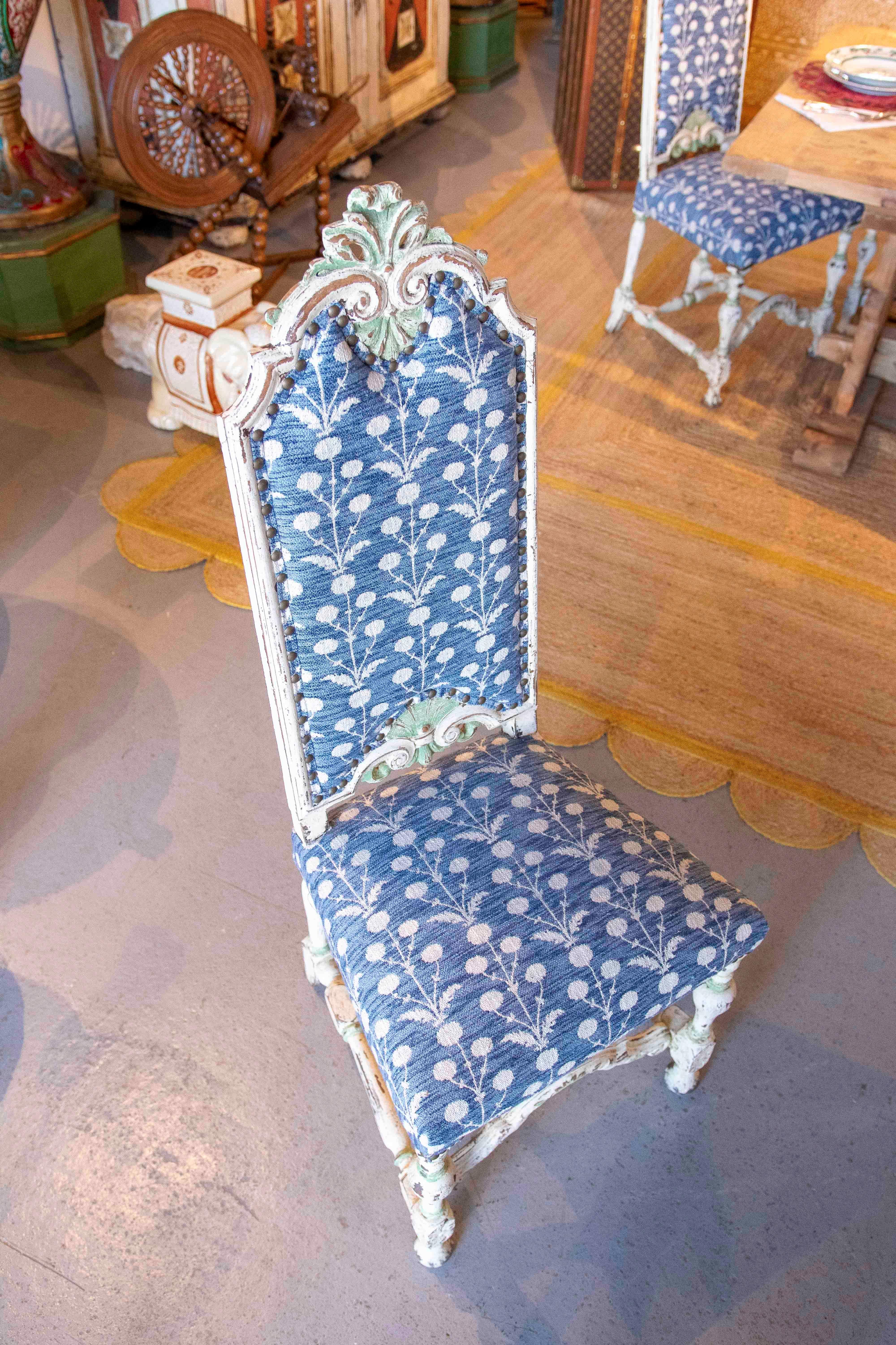 Magnífico conjunto de doce sillas antiguas, elaboradamente talladas en madera con acabado decapado blanco y detalles en verde claro. Cada silla tiene un respaldo alto y curvado, ricamente ornamentado en la parte superior, que le confiere elegancia y
