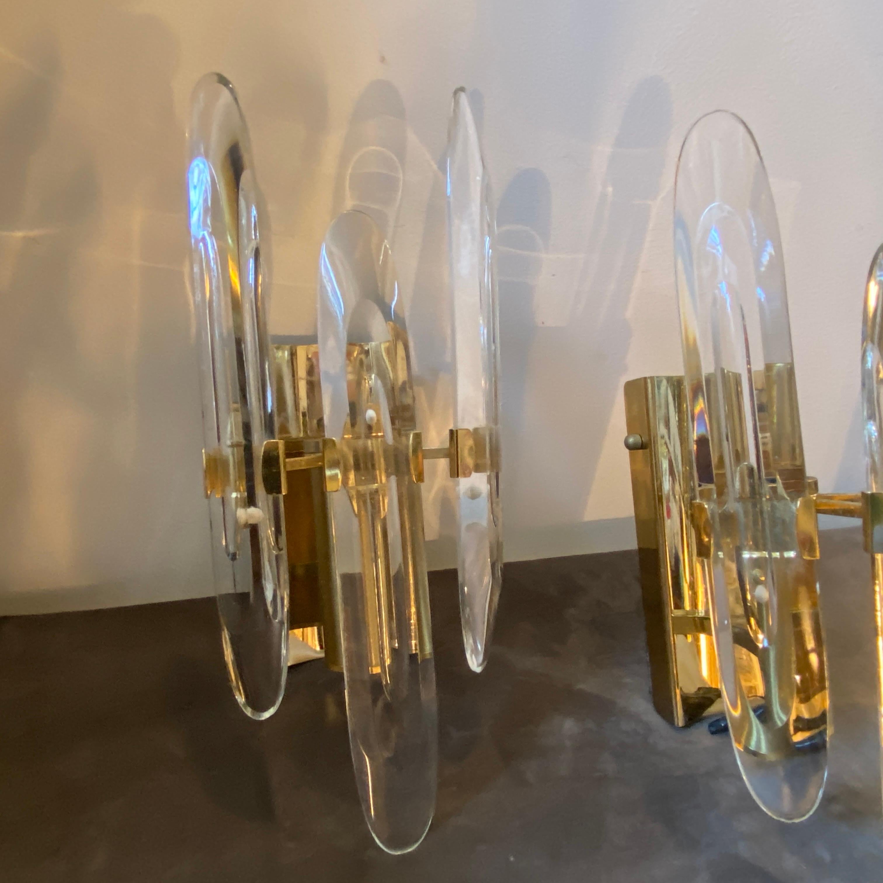 A pair of Mid-Century Modern brass and optical glass wall sconces designed by Gaetano Sciolari and manufactured in Italy by Sciolari Lighting. they work both 110-240 volts and need regular e14 bulbs. The optical glasses have the function of