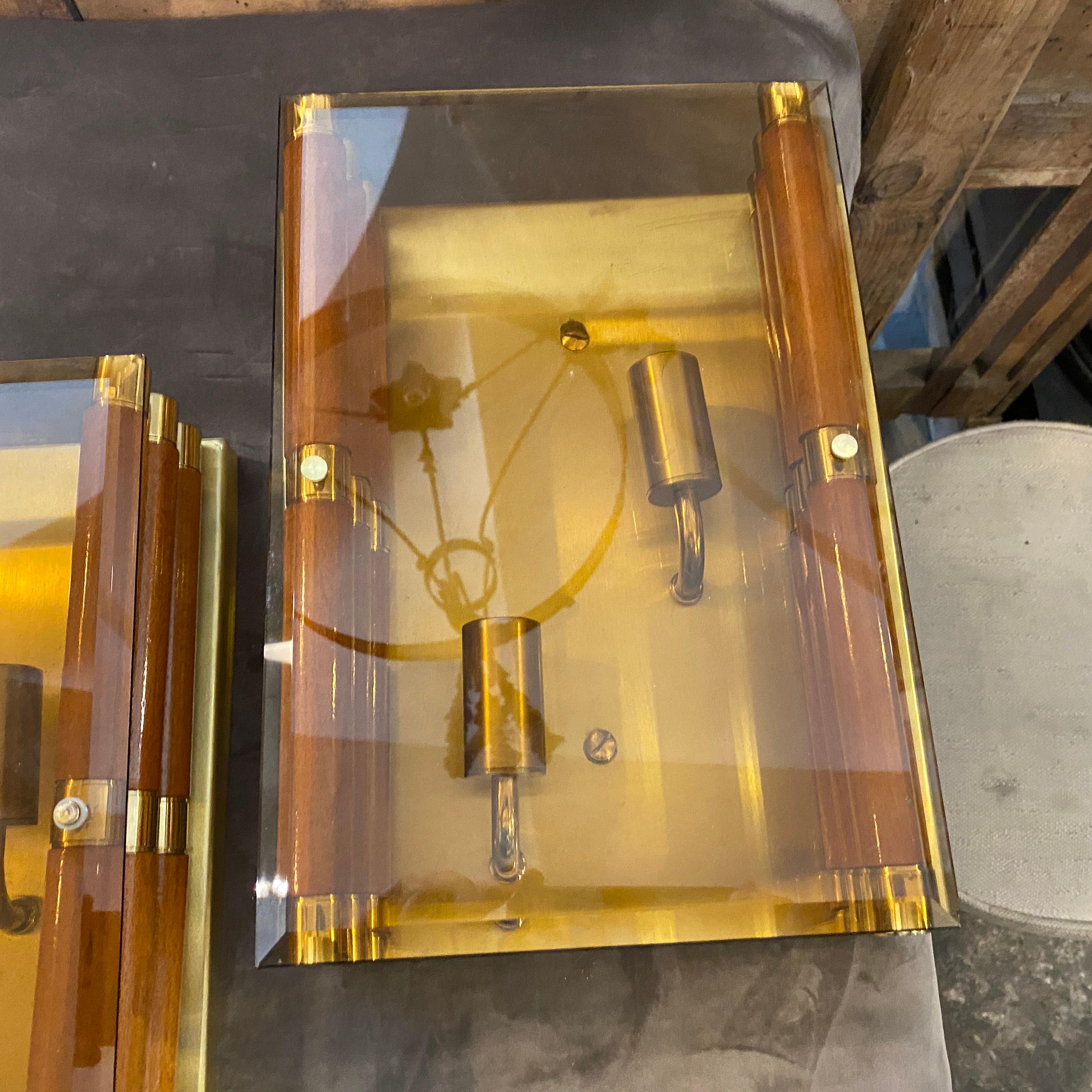 A pair of wood, brass and smoked glass wall sconces made in Italy in the Seventies, they are in perfect conditions, probably never used, they work 110-240 voli and need regular bulbs.