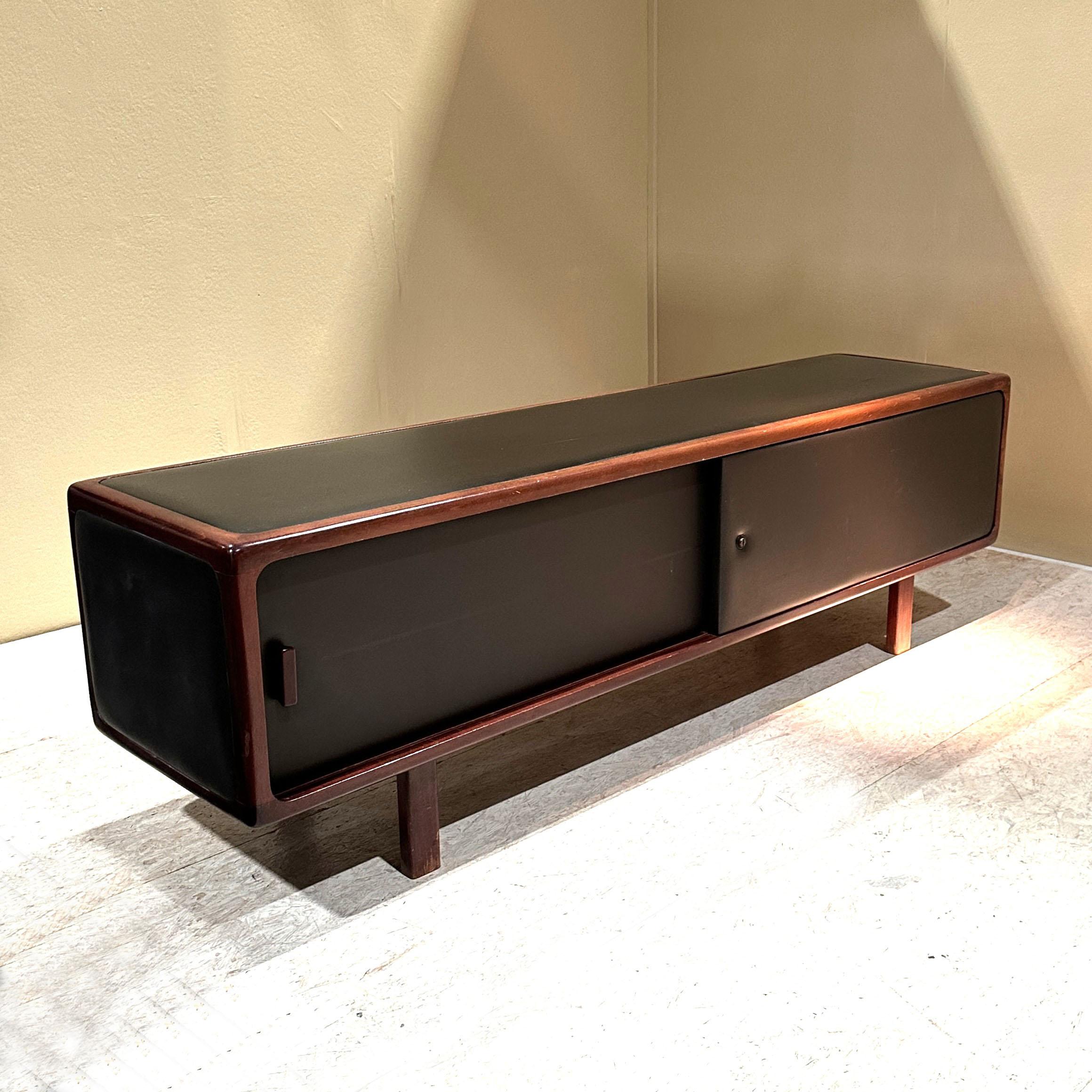 L'esclusiva credenza bassa autoportante è costruita in legno, probabilmente faggio tinto in mogano, e rivestita in pelle marrone scuro, quasi nera, su tutti i lati; è attribuita a Bulo, Belgio, anni '70. Questo design minimalista si basa sulla