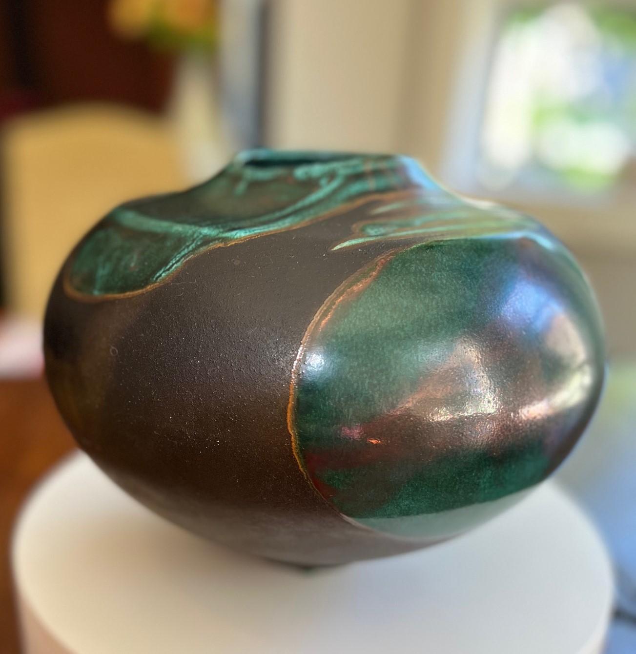 Vaso d'epoca firmato e numerato realizzato a mano dal maestro di ceramica raku Tony Evans (1942-2009) Cali. Questo recipiente raku ha una forma appiattita e sferica con un corpo largo e un collo stretto. Il pezzo presenta uno smalto lucido verde e