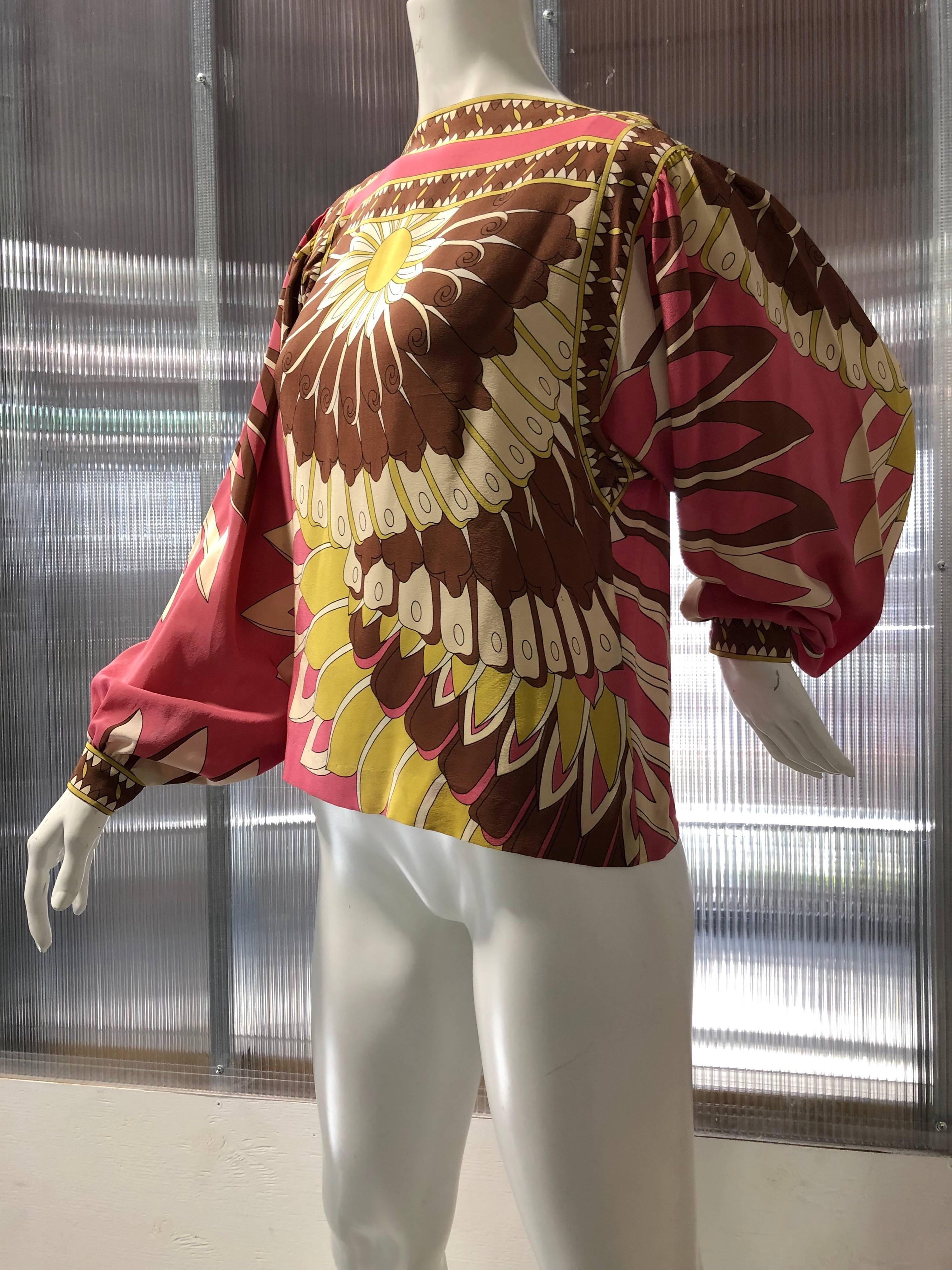 This Emilo Pucci-esque 1970s silk crepe lantern sleeve blouse is covered in a fantastic large scale abstract floral pattern. Pinks, yellows and browns make up the color scheme.  Made for Lord and Taylor.  Buttons at cuffs and neck. Fits up to a size