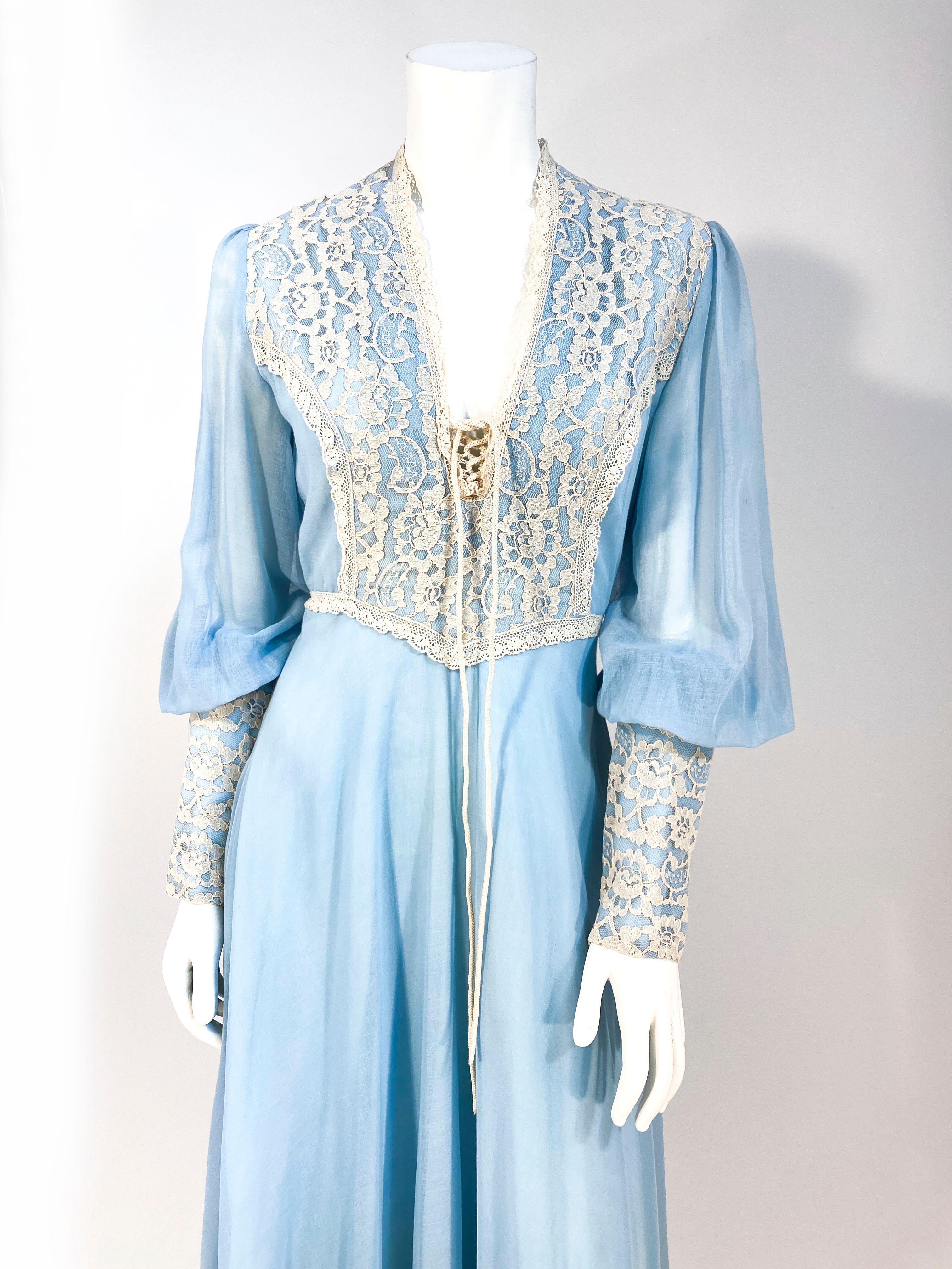 1970s sky blue full length cotton day dress with an ecru lace bodice and elongated cuffs. Each cuff has a long zip closure that allows for the bishop sleeves to have a full effect. The deep v-neckline has an adjustable cord closure. The bodice of