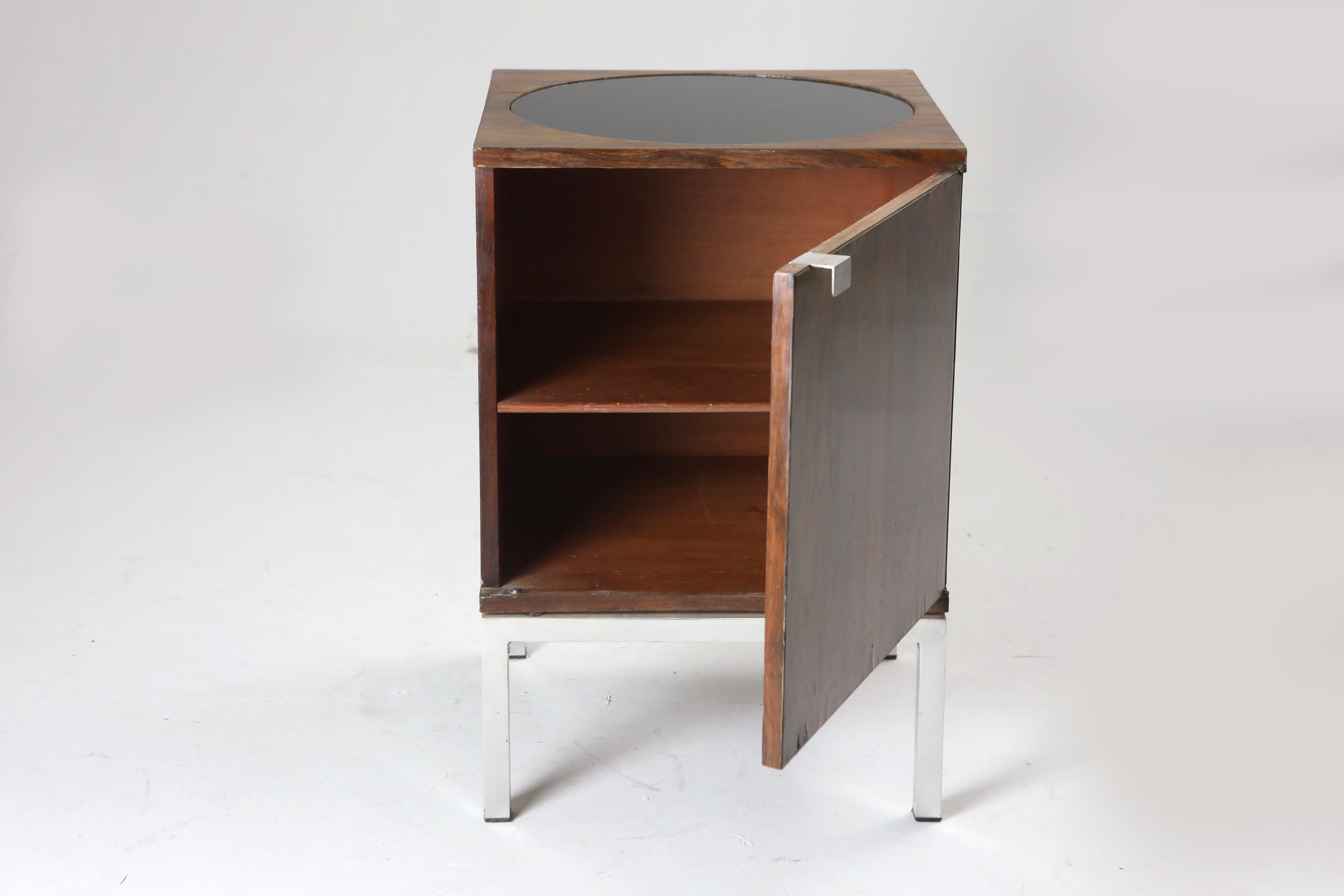 Mid-Century Modern Small Cabinet in Wood by Forma Manufacture, Brazil 1970s.

1970's Small vintage wood cabinet by the Brazilian Forma Manufacture featuring a circle painted glass top and chromed iron feet.