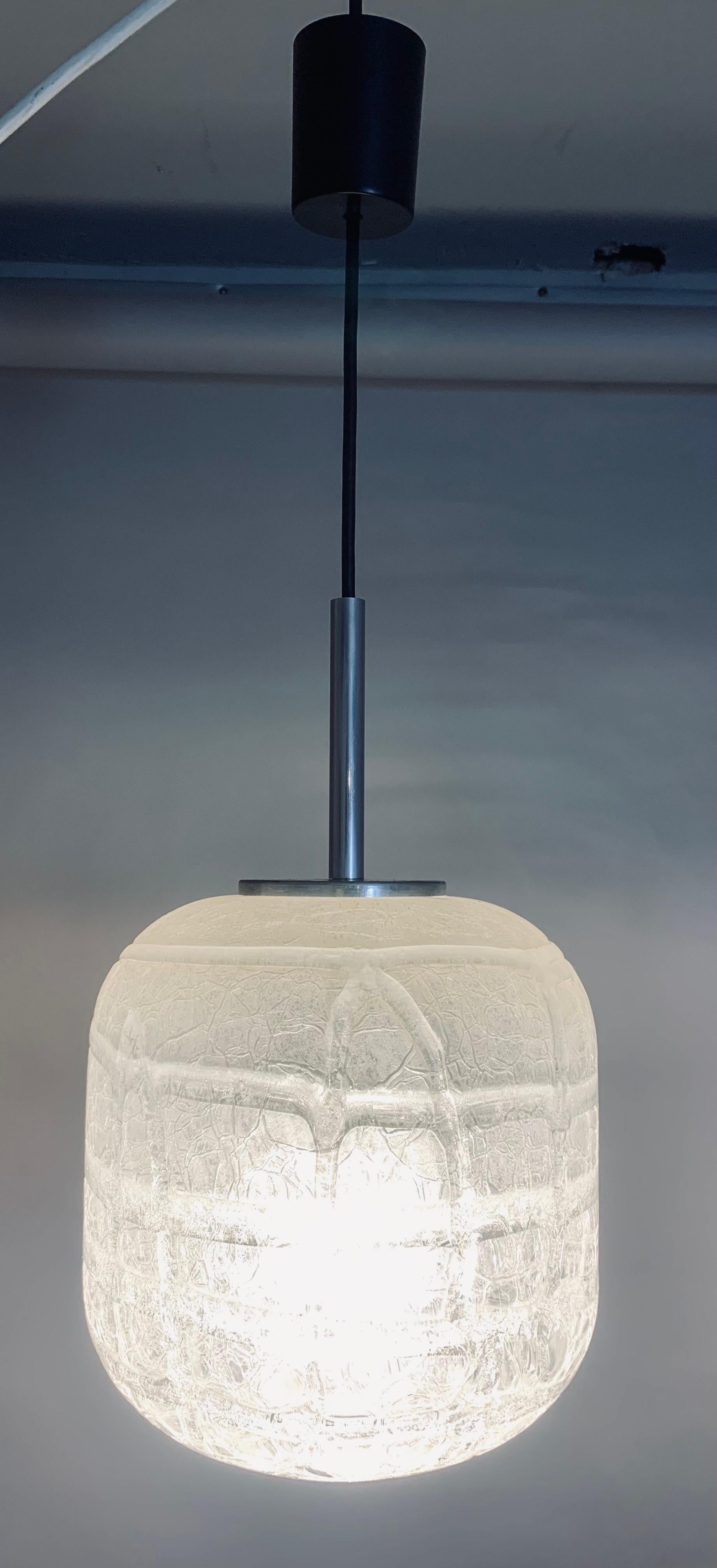 A small but perfectly formed crackled iced-glass cylindrical pendant hanging light made in the 1970s by Doria Leuchten in Germany. The shade hangs from a black flex with a matching ceiling cup which hides the wires where they connect to the ceiling.
