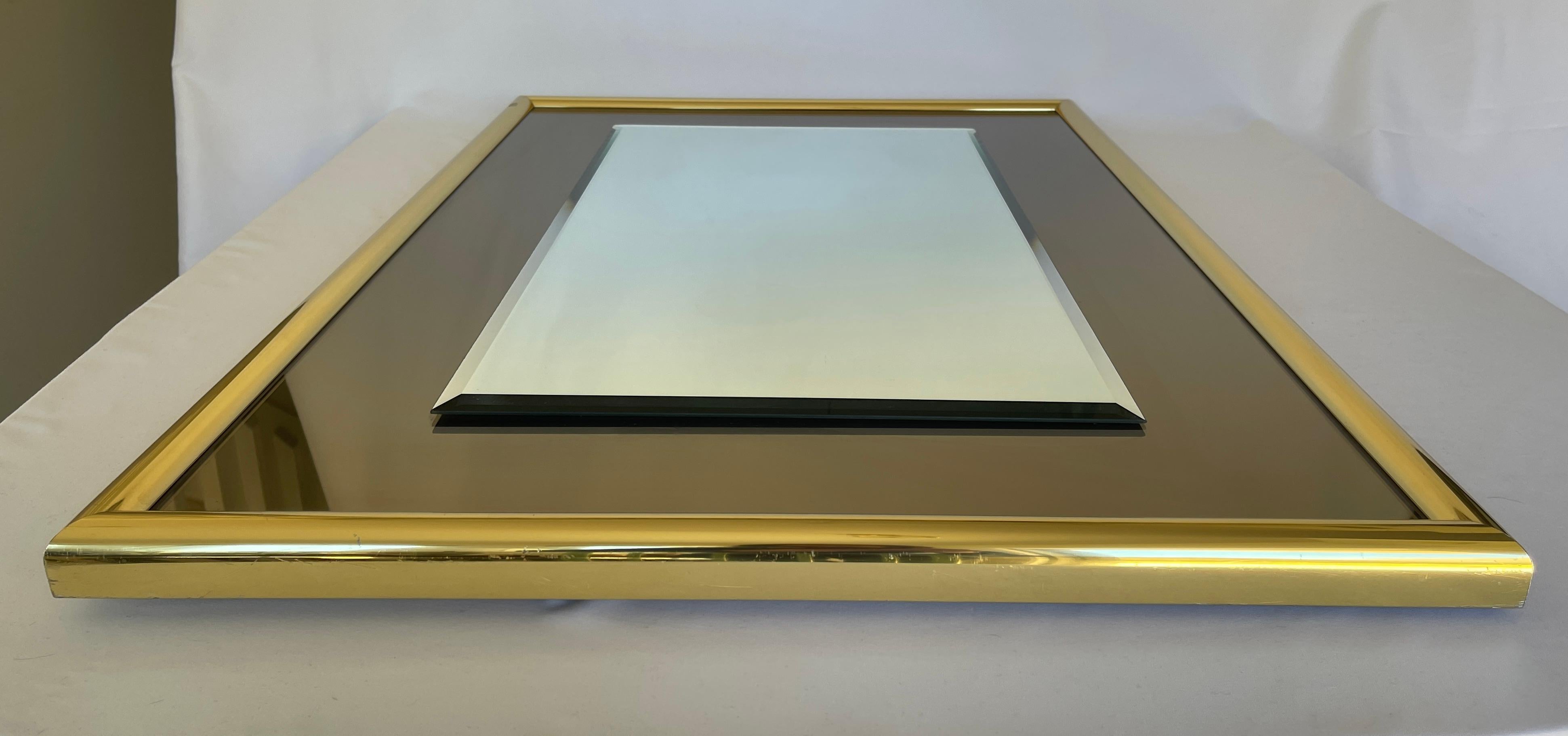 1970s rectangular mirror with smoke glass border and brass frame. 
May be hung vertically or horizontally.