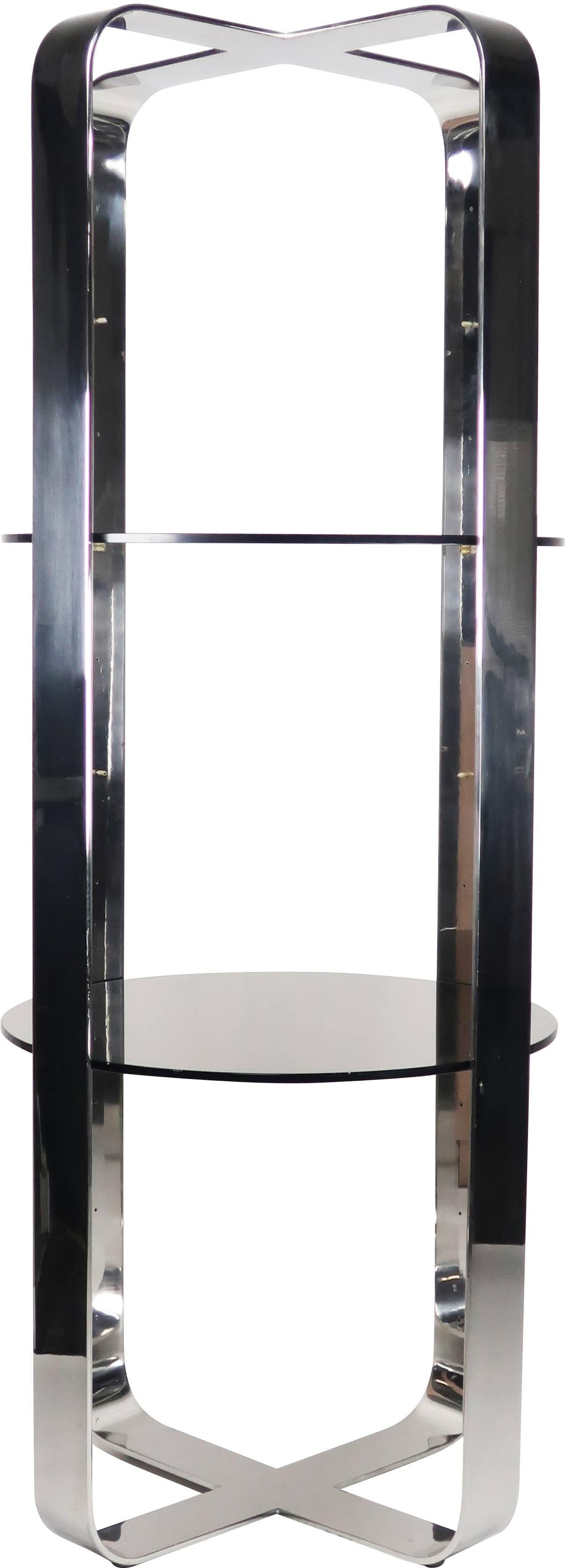 An amazing 1970s space age mod chrome and smoked glass étagère in the style of Milo Baughman and Design Institute of America. With a heavy round frame of polished flat chrome with smoked glass shelves, this unit is over 6 feet tall and shines as the