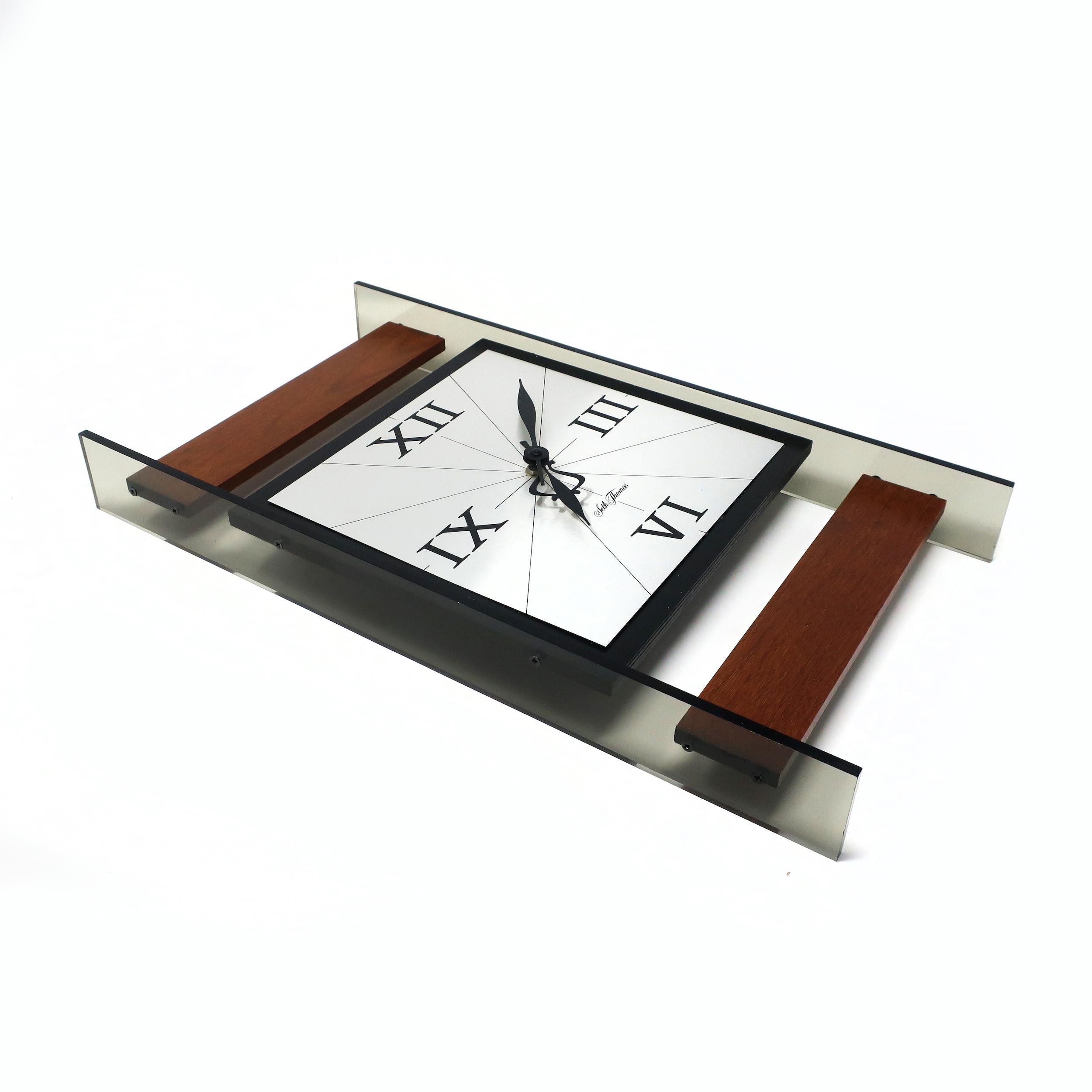 A classically mid-century modern Seth Thomas wall clock. Made of smoked lucite with teak accents, silver face, and black hands. Marked 