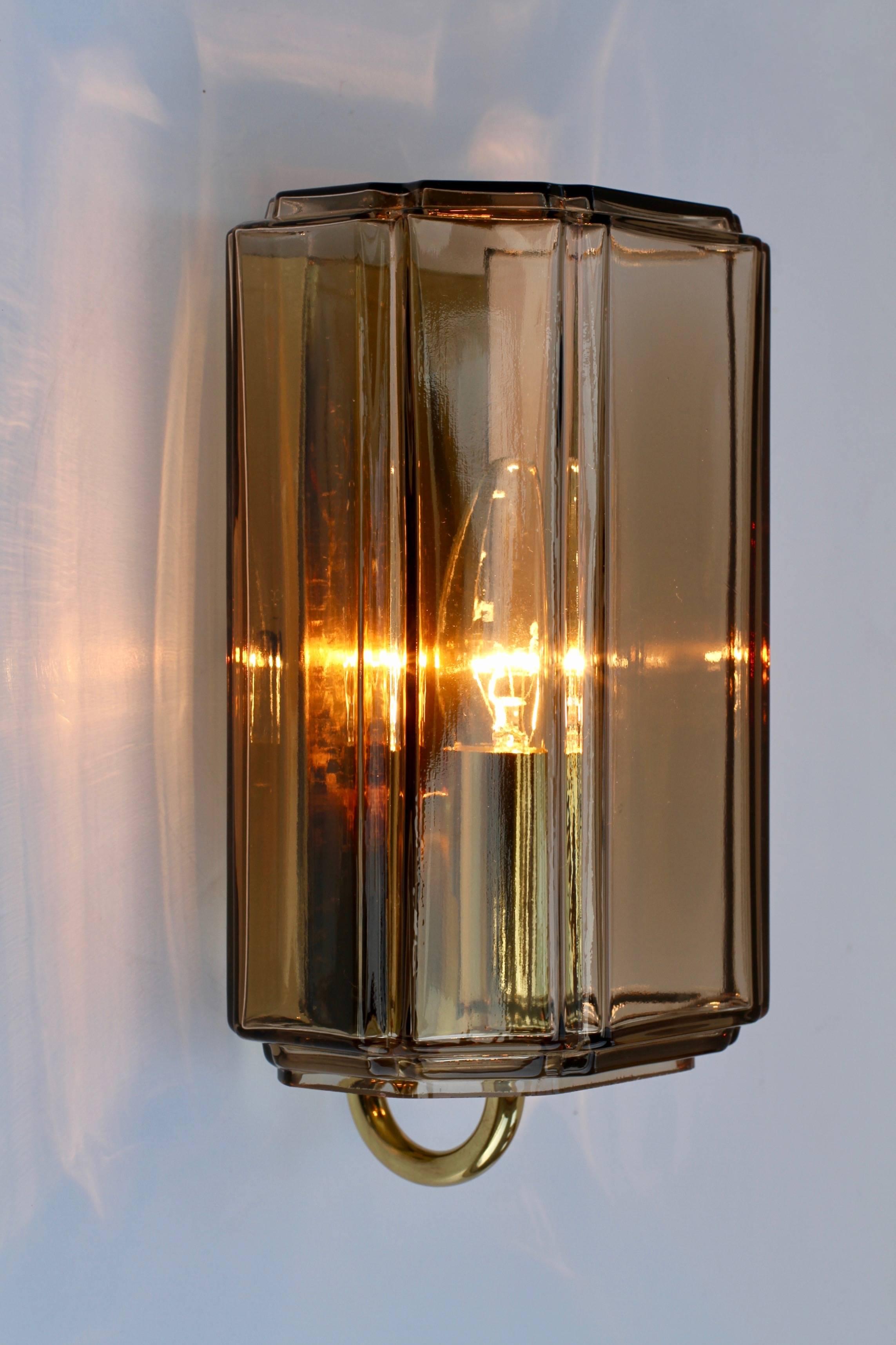 One of a set of three wonderful German wall-mounted single socketed light fixtures, sconces or lamps by Glashütte Limburg, circa 1965-1975. The geometric form of the smoked amber toned / topaz colored/coloured mouth blown glass illuminates