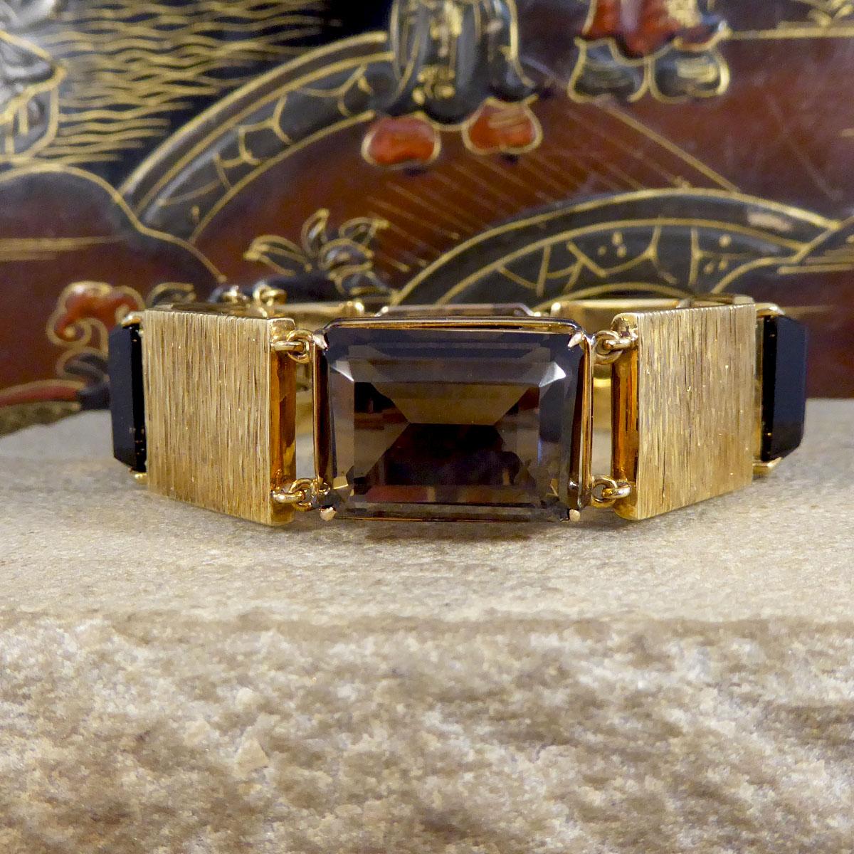 This astonishingly crafted 9ct Yellow Gold bracelet has been hand made in the 1970's with such a great style which is typical for this time. Each panel of the bracelet is alternating between a large Smokey Quartz in a four claw setting, and a 9ct