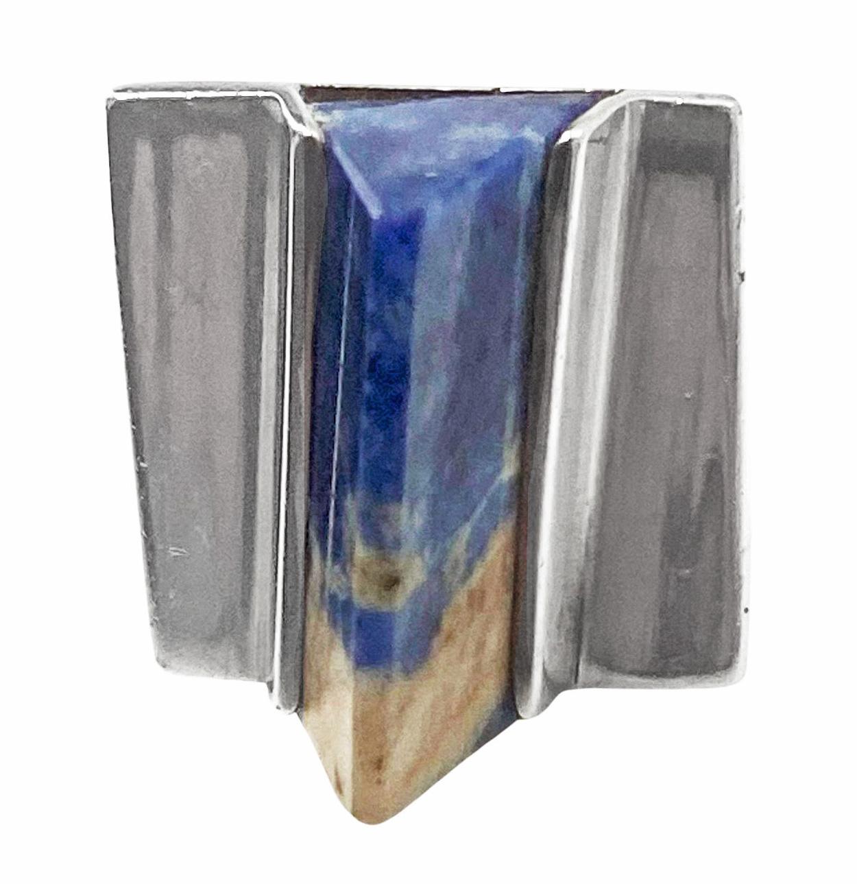 1970’s Sodalite and Sterling Ring. Centering on a five-sided triangular sodalite, within a square-shaped silver mount. Sodalite measuring approximately 21.4 x 8.5 x 12.3 mm. Size 6. Full English hallmarks for London 1970 J & P MMD. Magnus Maximus