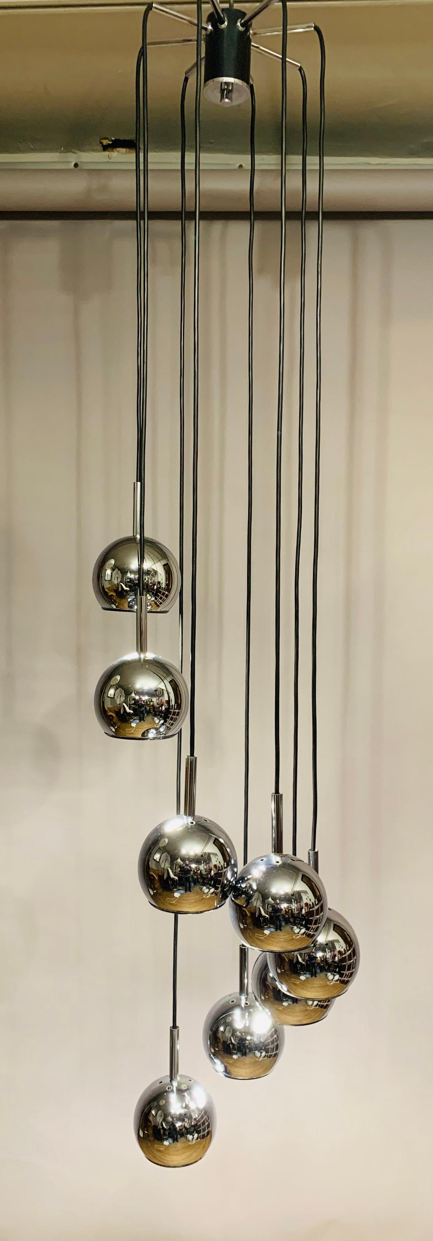 1970s, Space Age, German hanging ceiling light with eight tiers of cascading chrome globes each suspended from a black wire flex. An E14 screw in bulb fits within each globe which are white inside with a feature black rim around the outside. The