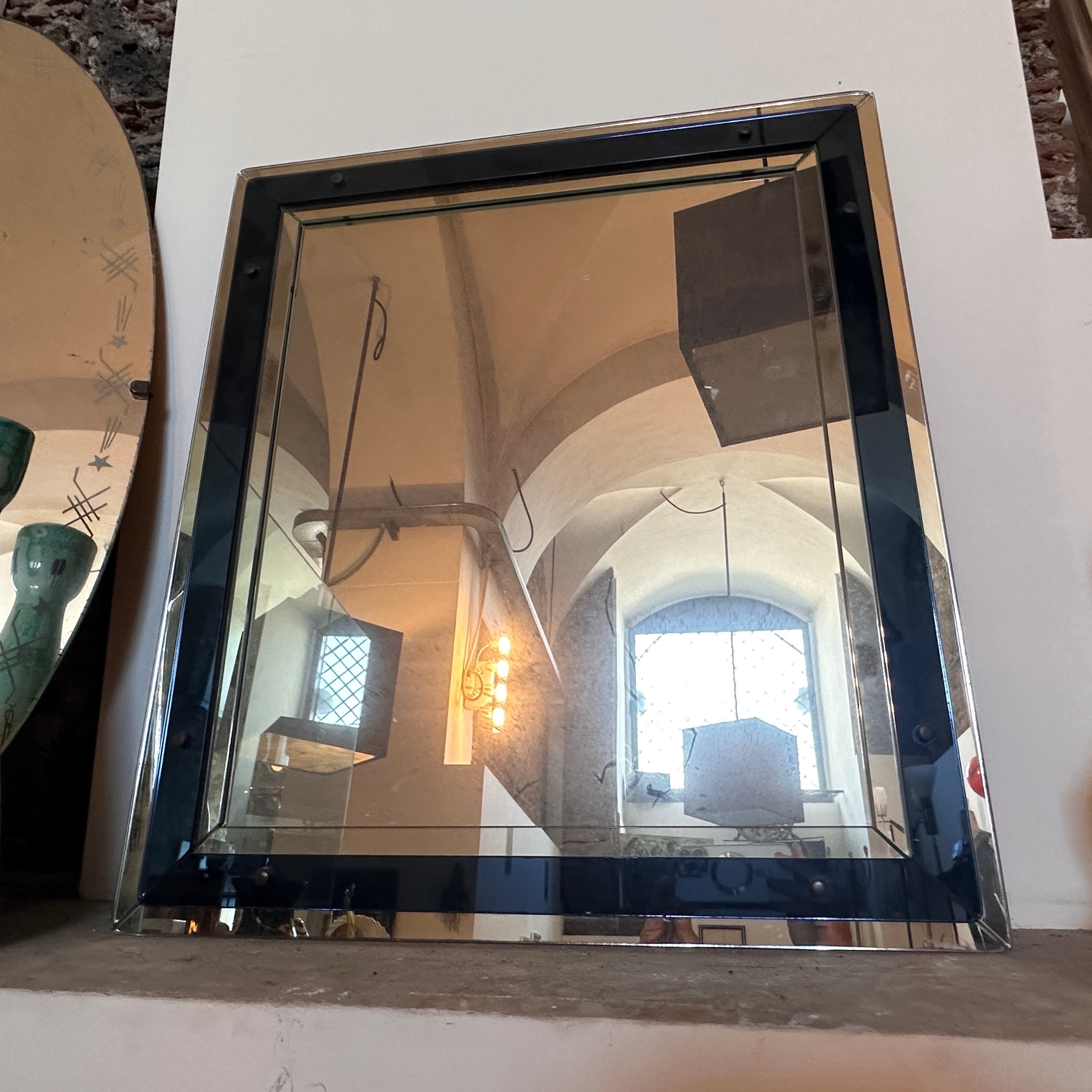 A Blue Glass RectangularWall Mirror by Cristal Arte is a stylish and iconic piece of Italian design from the mid-20th century. The mirror frame is made of blue glass, which was a popular choice for Space Age design in the 1970s. The blue glass has a