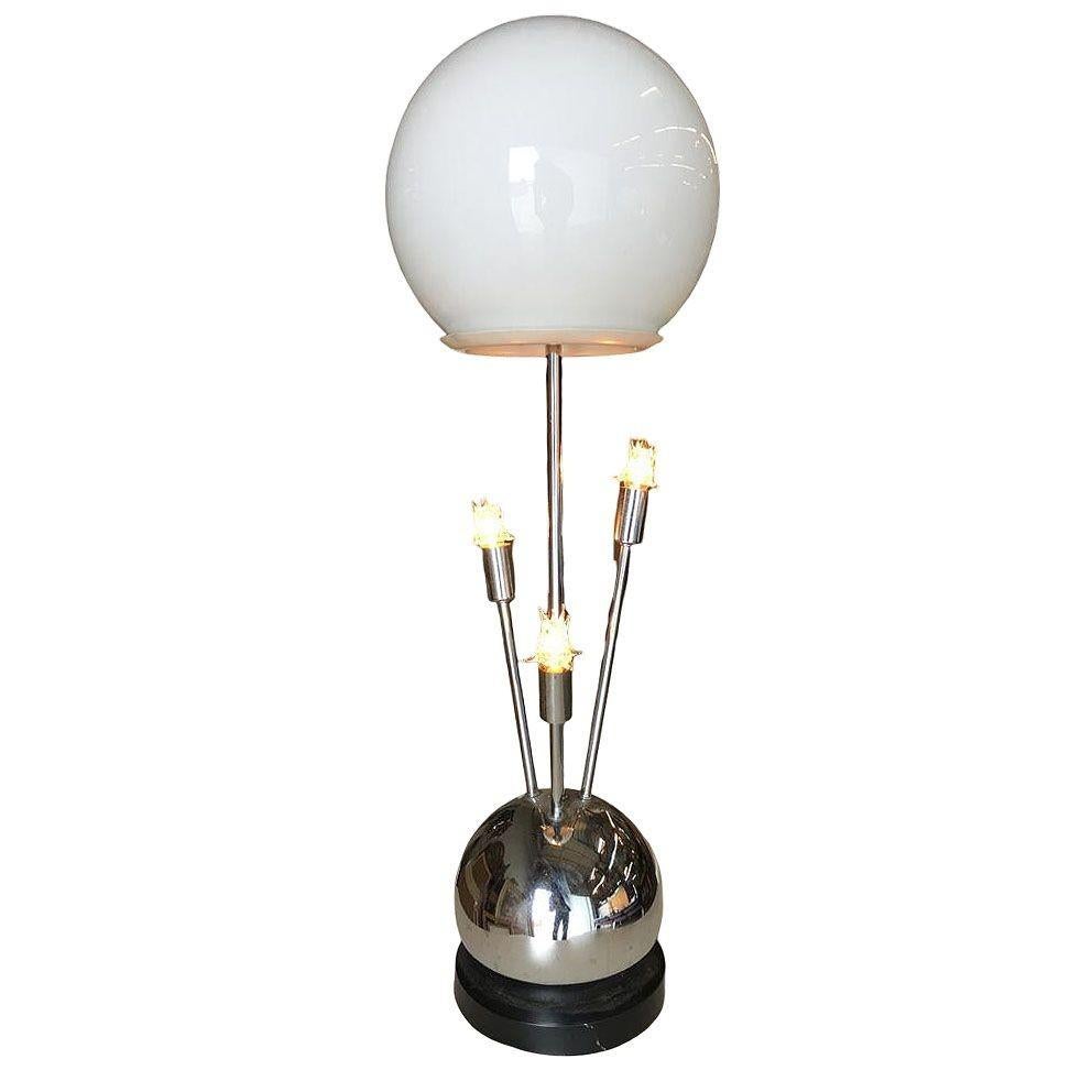 1970s era Space Age chrome ball table lamp with glass globe main light and 3 accent lights branching out from the chrome ball base, all fixed to a black enamel base. It features a 3-way switch that lights the top, sides, or top and sides together.