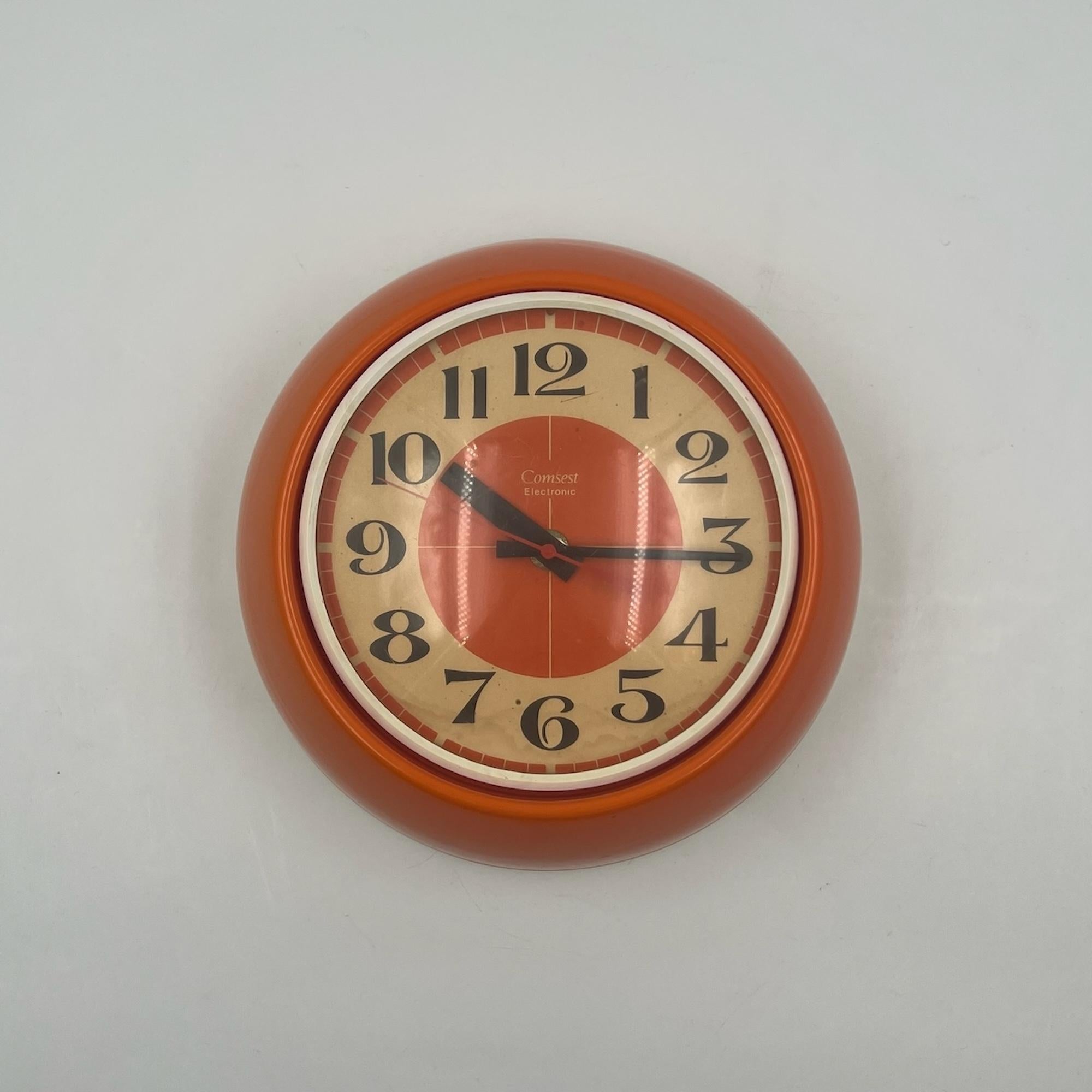 Add a touch of retro-futuristic charm to your decor with this space age wall 70s clock by Comsest, crafted in Italy. This eye-catching vintage piece features a bright orange plastic structure, typical of the vibrant color trends of the era. The