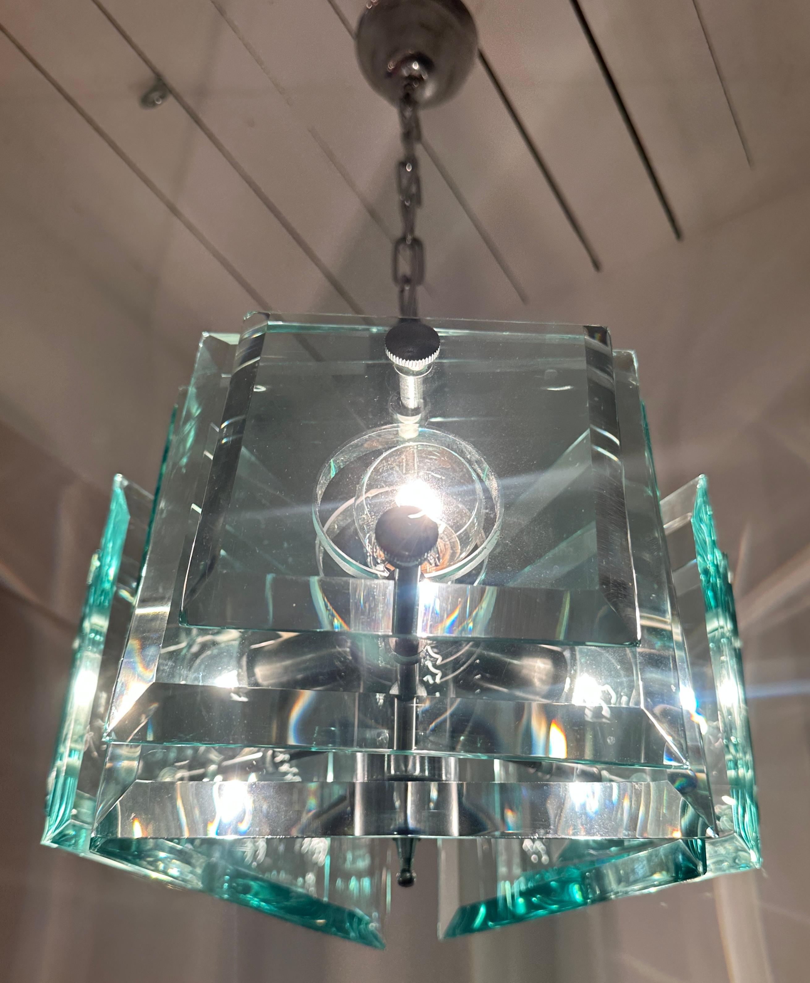 A stunning space-age 1970s Italian chandelier manufactured by Lupi Cristal Luxor. The triangular shaped light features, on each side, three bevelled, high-quality and thick squares of very pale green crystal glass.  The glass diminishes in size with