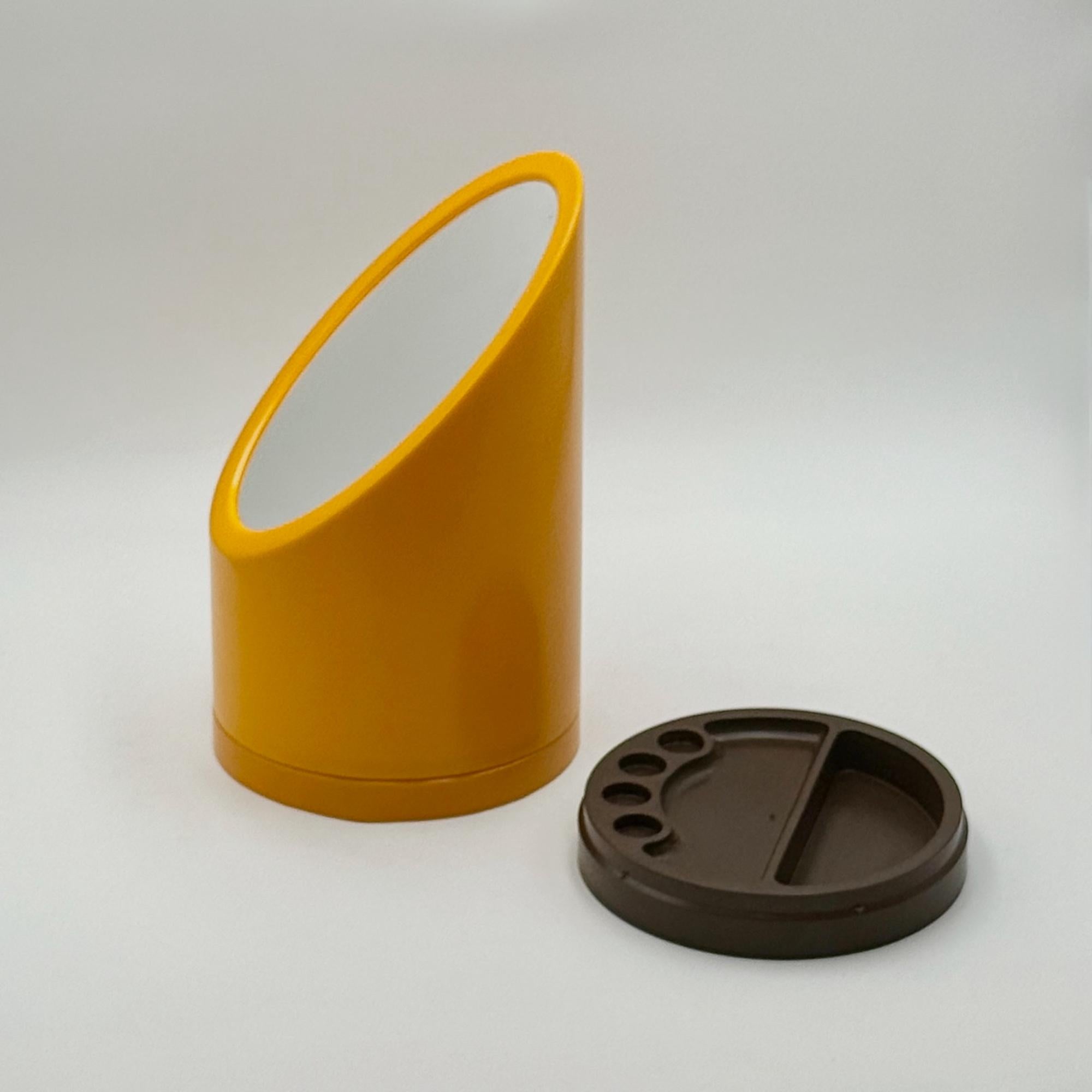 Ce miroir de table pour rouge à lèvres, datant des années 1970 et fabriqué en Hollande, est une œuvre compacte en plastique pop qui allie l'utilité à la présence sculpturale. Le corps cylindrique jaune est coupé en diagonale de sorte que la surface