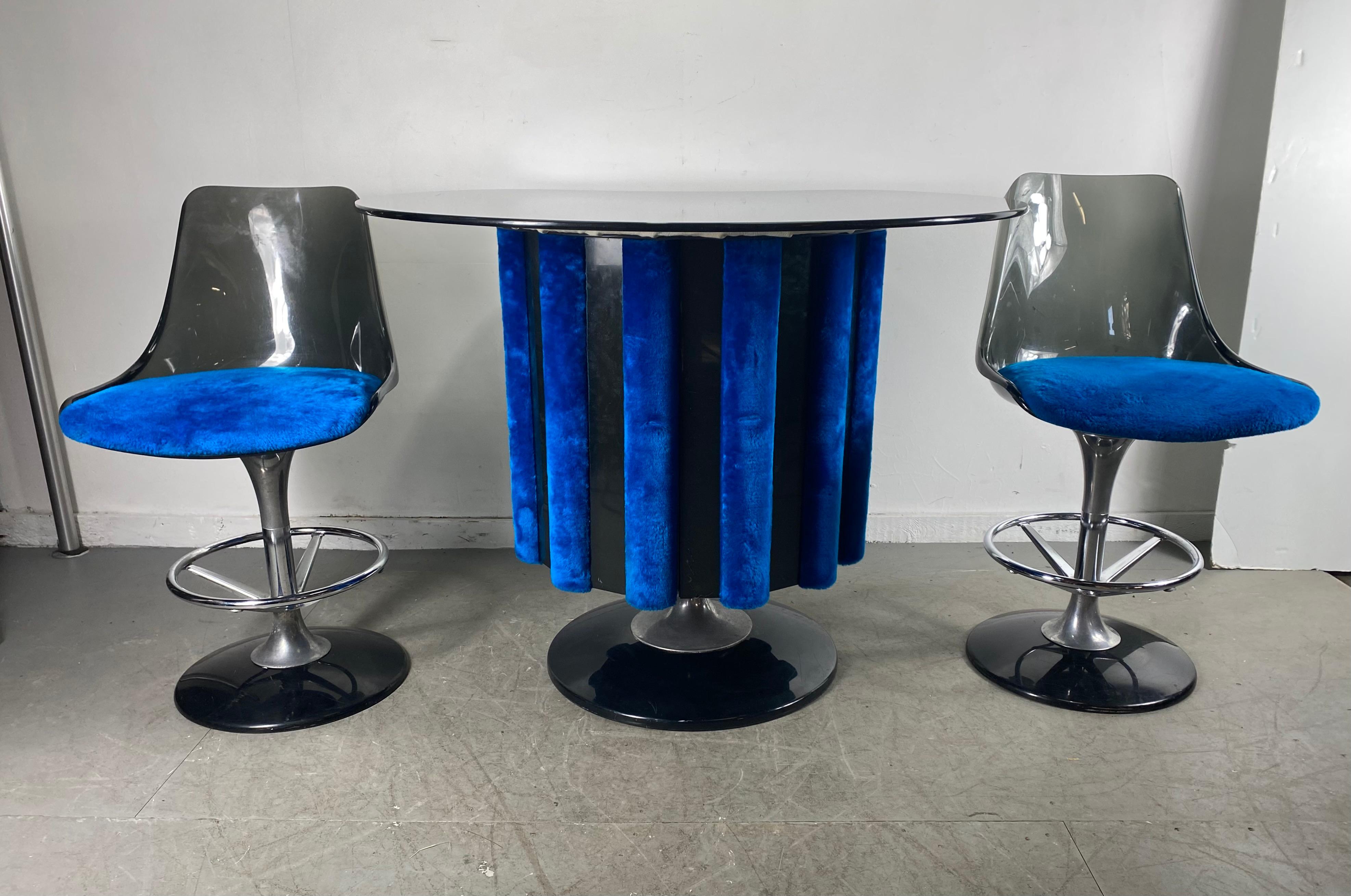 A midcentury Space Age three-piece pedestal dry bar with two accompanying bar stools from Chromecraft. Created with alternating acrylic panels and rolled blue fur fabric panels. Supported by a chrome and black base. The stools are smoked gray