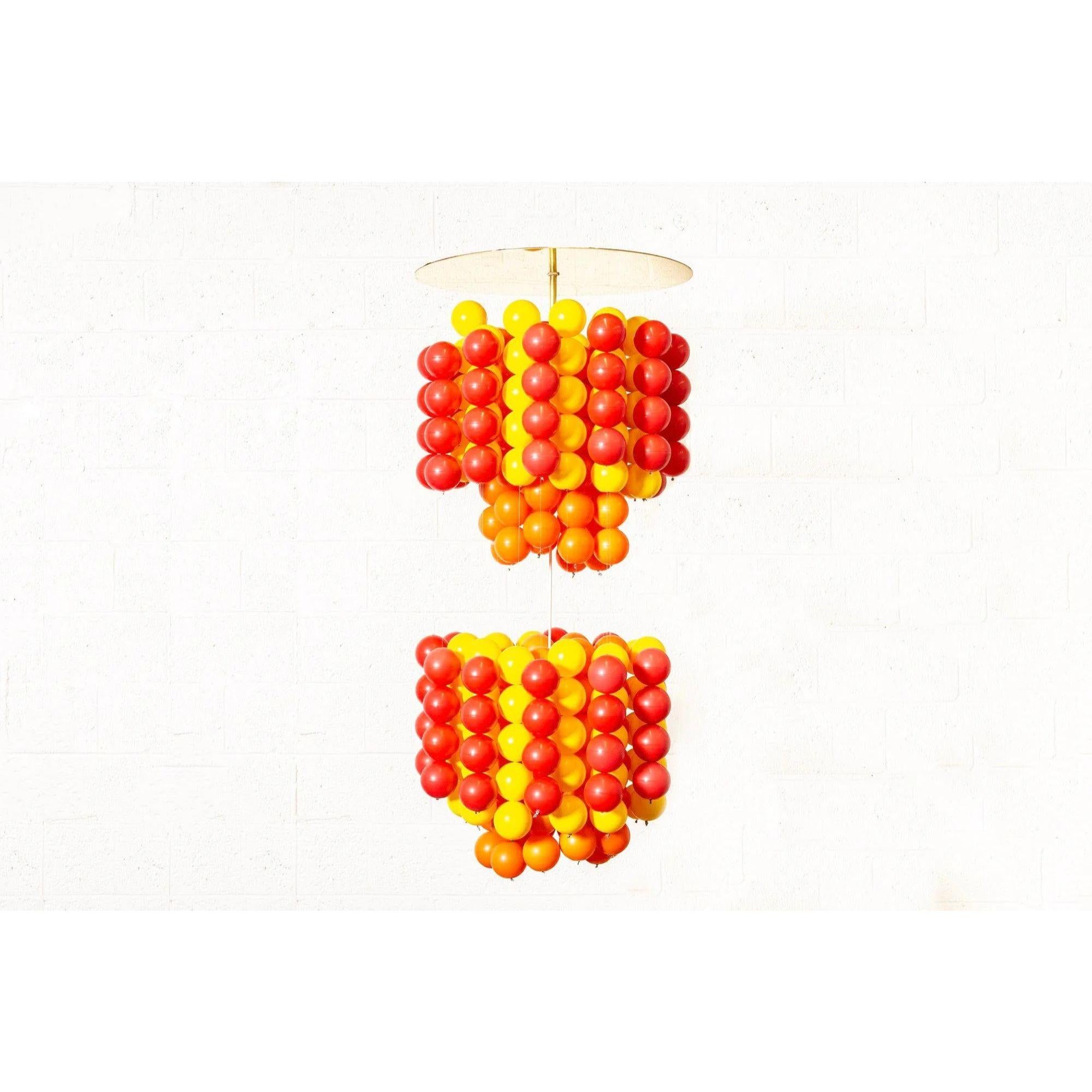 This large 50” midcentury Space Age multicolored ball chandelier pendant in the manner of Verner Panton is circa 1970 and has incredible Space Age style. The design features layers of red, orange and yellow nylon plastic balls suspended on nylon