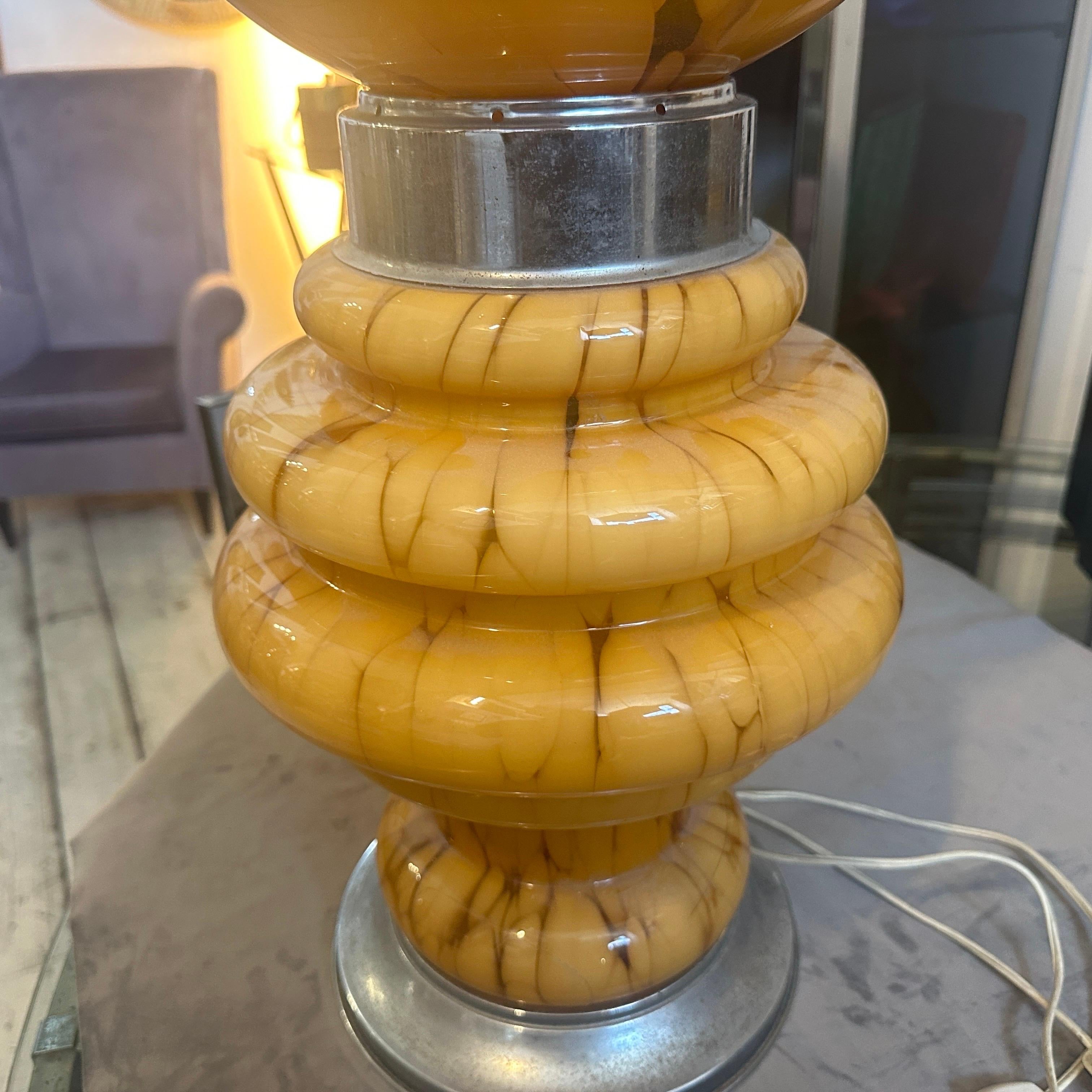 An iconic table lamp manufactured in Italy by Mazzega, chromed metal and yellow murano glass are in good vintage conditions. It works both 110-240 volts and needs regular e27 bulb. This table lamp by Mazzega is a striking piece that combines the