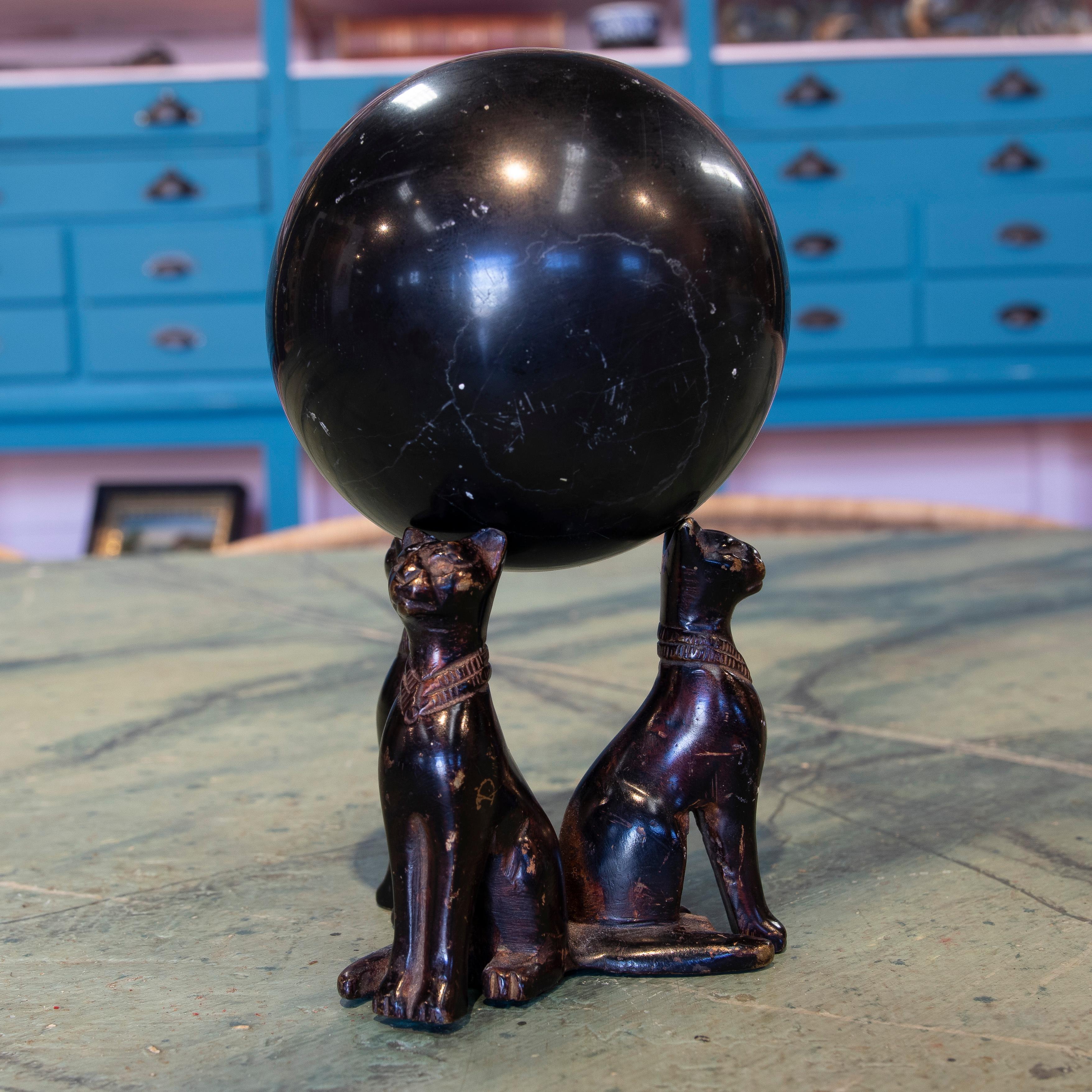 Schwarze Marmorkugel aus den 1970er Jahren aus Spanien auf einem Sockel mit drei bronzenen Katzen.

 