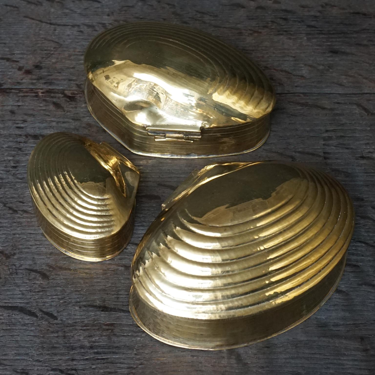 These heavy vintage brass clam shell trinket boxes would make a great gift.
The two smaller ones fit in the largest, like a nesting set.
All boxes have hinged lids.
    