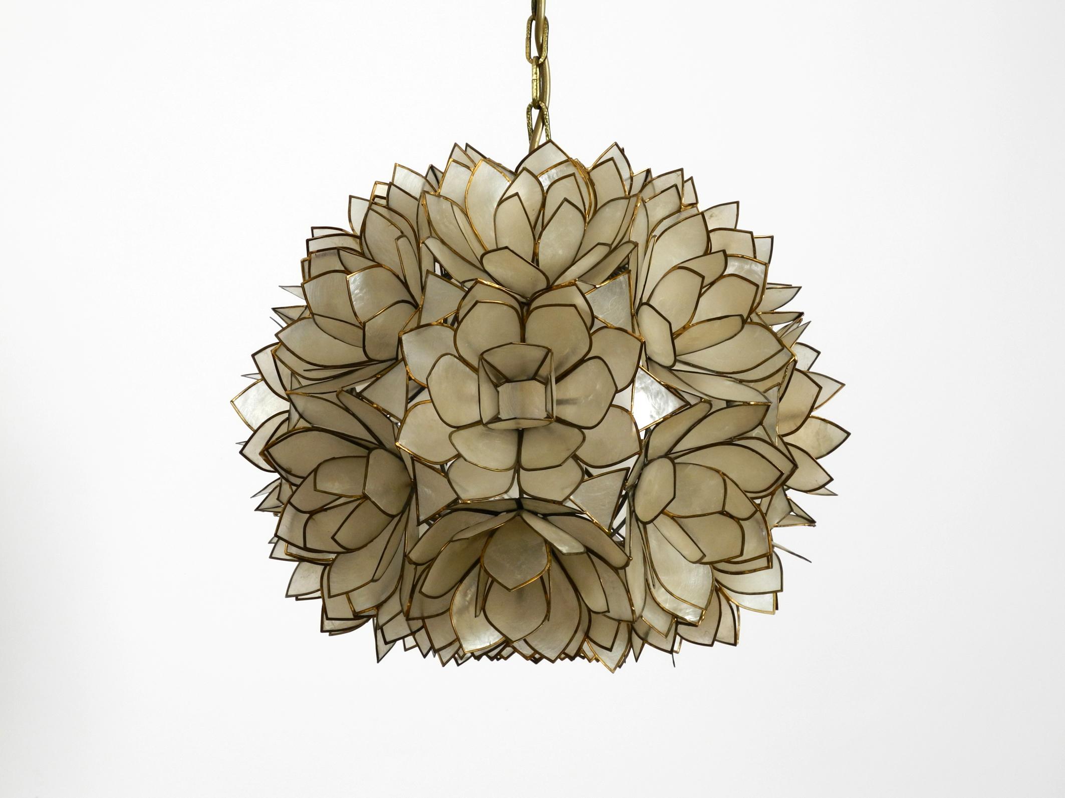 Very elegant pendant lamp in spherical shape made of mother of pearl. 
Like a bunch of flowers or blossoms. Great rare design of the 1970s. 
Very high quality workmanship.
Metal frame is hung on a brass chain and brass canopy. 
One E27 socket