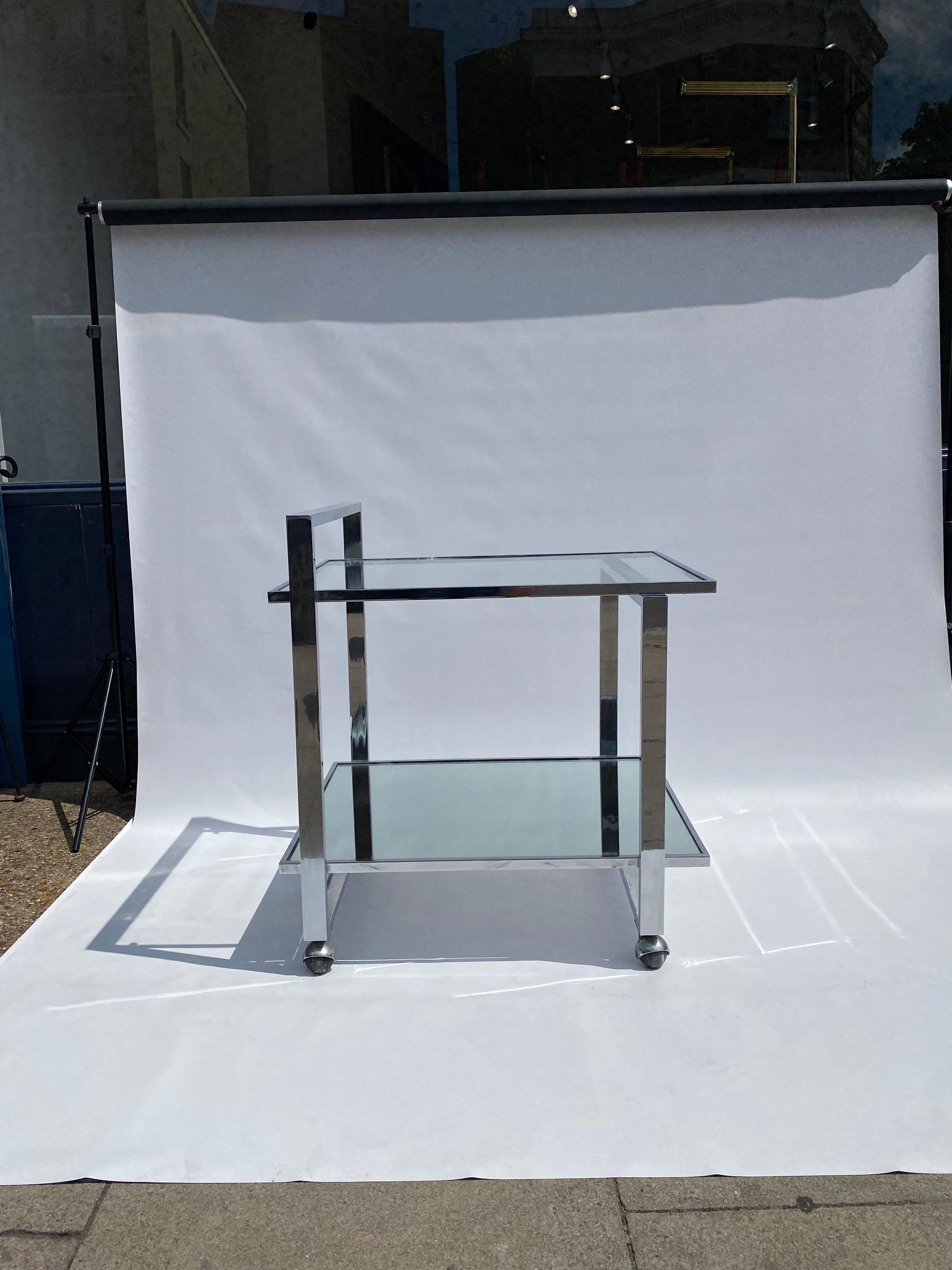 A stylish vintage 1970s nearly square bar cart larger than the usual ones, in the manner of Renato Zevi and Romeo Rega. It usually attributed to Romeo Rega.

The chrome frame bars support two tieres of framed glass and mirror panels for the bottles