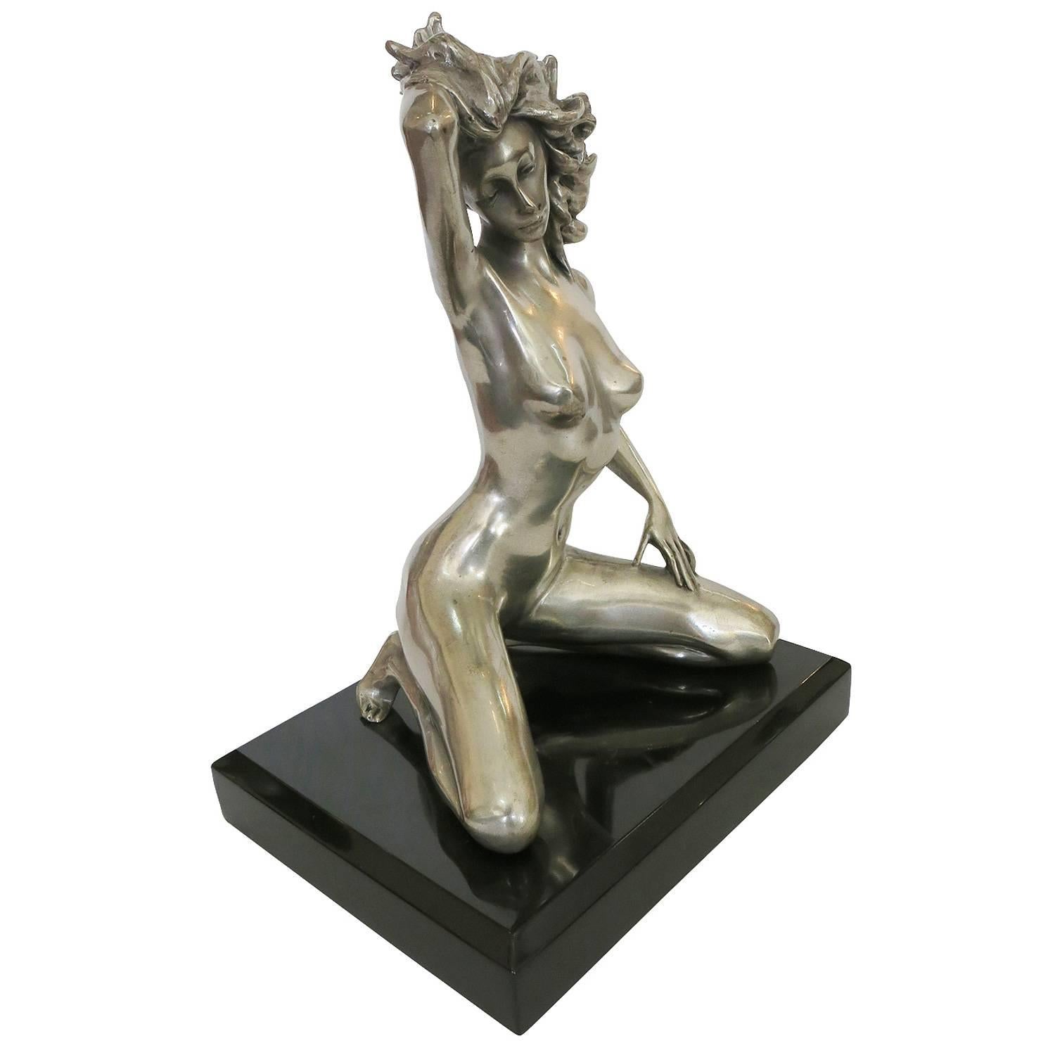 1970s style erotic bronze re-cast of a kneeling nude woman with one hand resting against her wind blown hair, one hand on her leg. Kneeling on a black mirror-finished marble square base, unsigned

Dimensions: 11? H x 8? W x 6.5? D.

Product