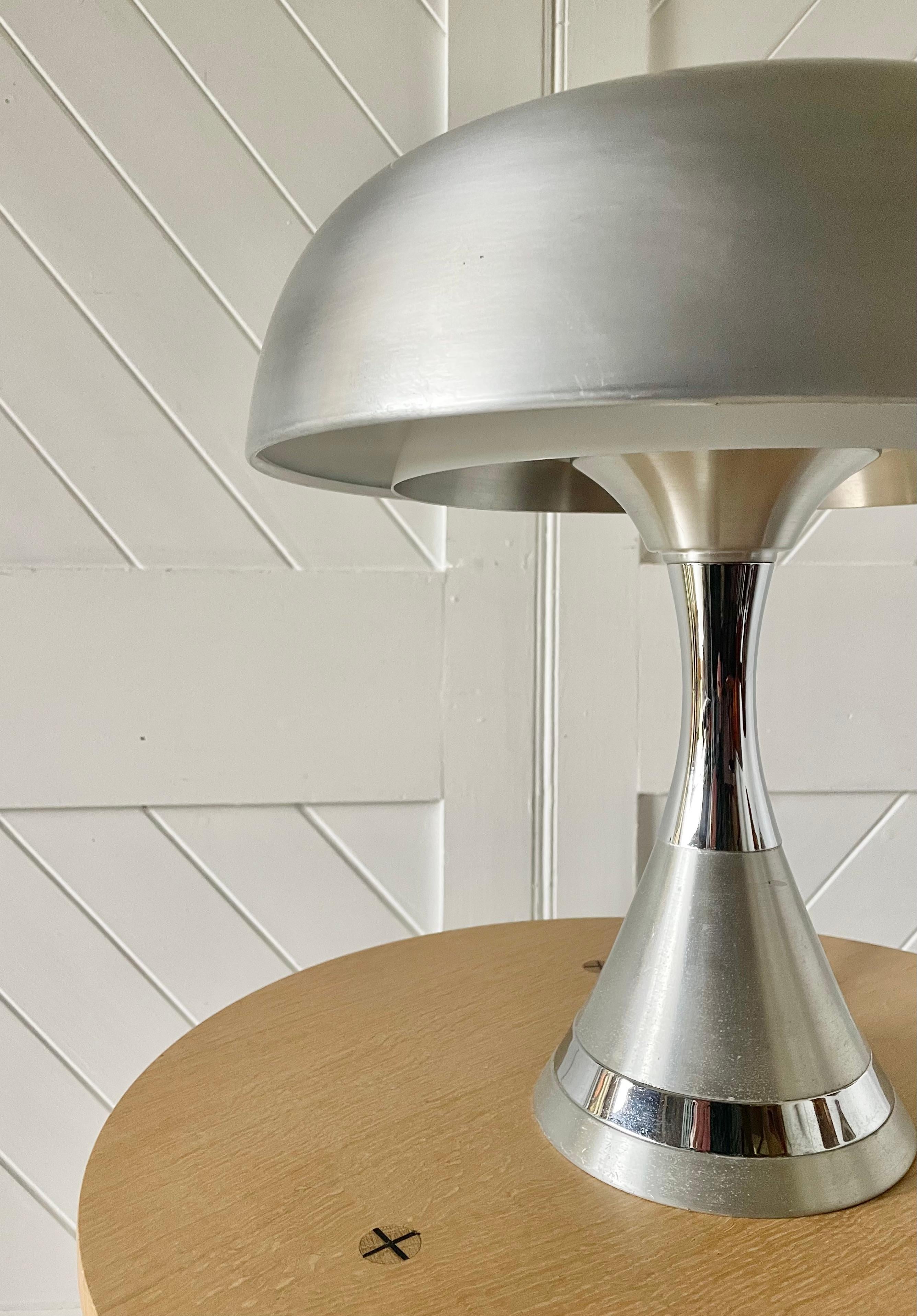 Lámpara de mesa setentera con forma de seta, de aluminio cepillado y cromo. 3 bombillas interiores y una superior. 

Diseño atribuido a Harvey Guzzini Italia años 70.

Una elegante lámpara de sobremesa de los años setenta.

pat probado listo para