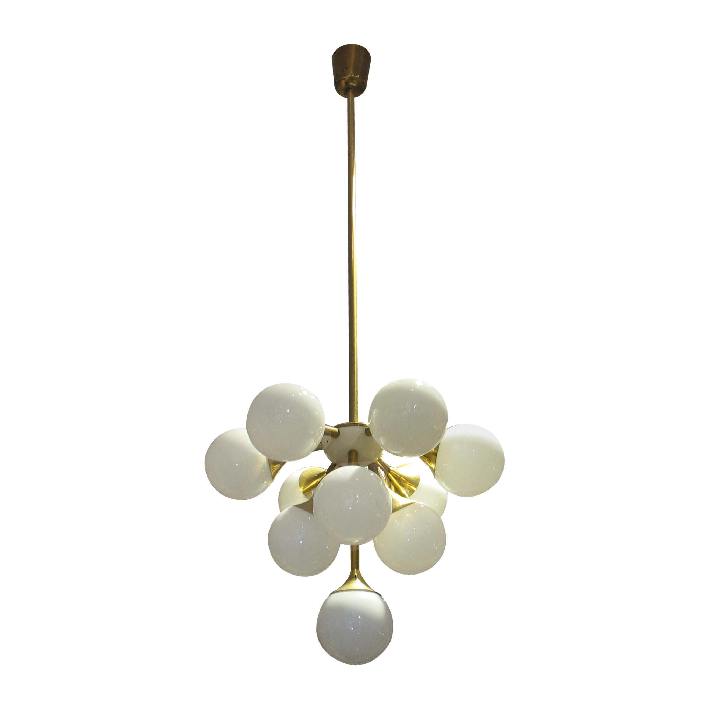 This Swedish ceiling light from the 1970s is a stunning example of mid-century modern design. It features a brass structure with multiple opaline glass globes. The chandelier's sculptural form is both elegant and playful, with the globes arranged in