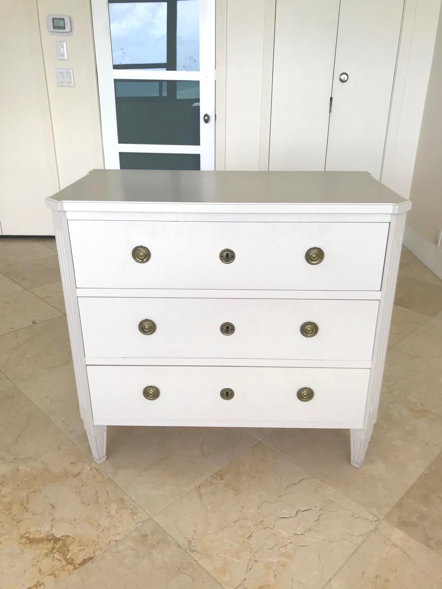 Swedish vintage chest of drawers. Fitted with three large spacious drawers. The chest features canted corners a prominent detail of Gustavian furniture, and has carved wood sides creating fluted accents. Raised on carved wood tapered legs and fitted