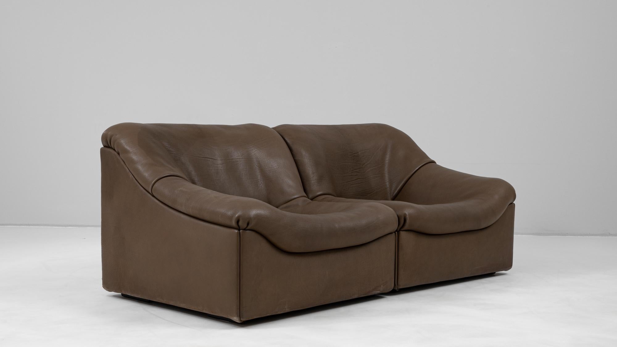 This pair of 1970s Swiss De Sede DS-46 leather armchairs showcases the brand’s hallmark craftsmanship and luxurious design. Upholstered in supple brown leather with a rich patina, the chairs embody comfort with their deep, low-slung seats and fluid,