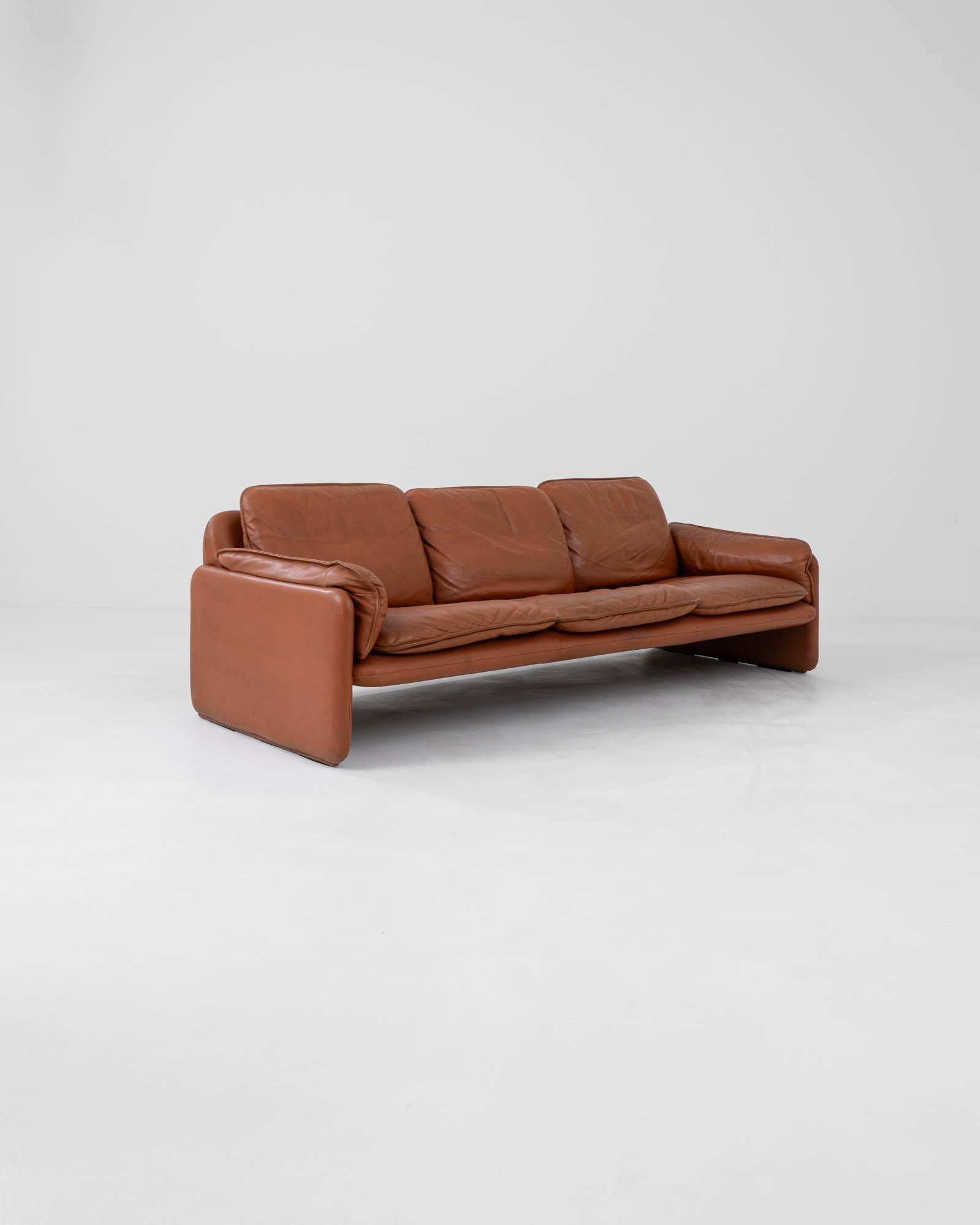Embrace the unparalleled luxury and timeless design of the 1970s Swiss leather sofa DS61 by De Sede, renowned for its dedication to quality and comfort. Crafted from rich, caramel-colored leather, this sofa features a plush, deep seating area that