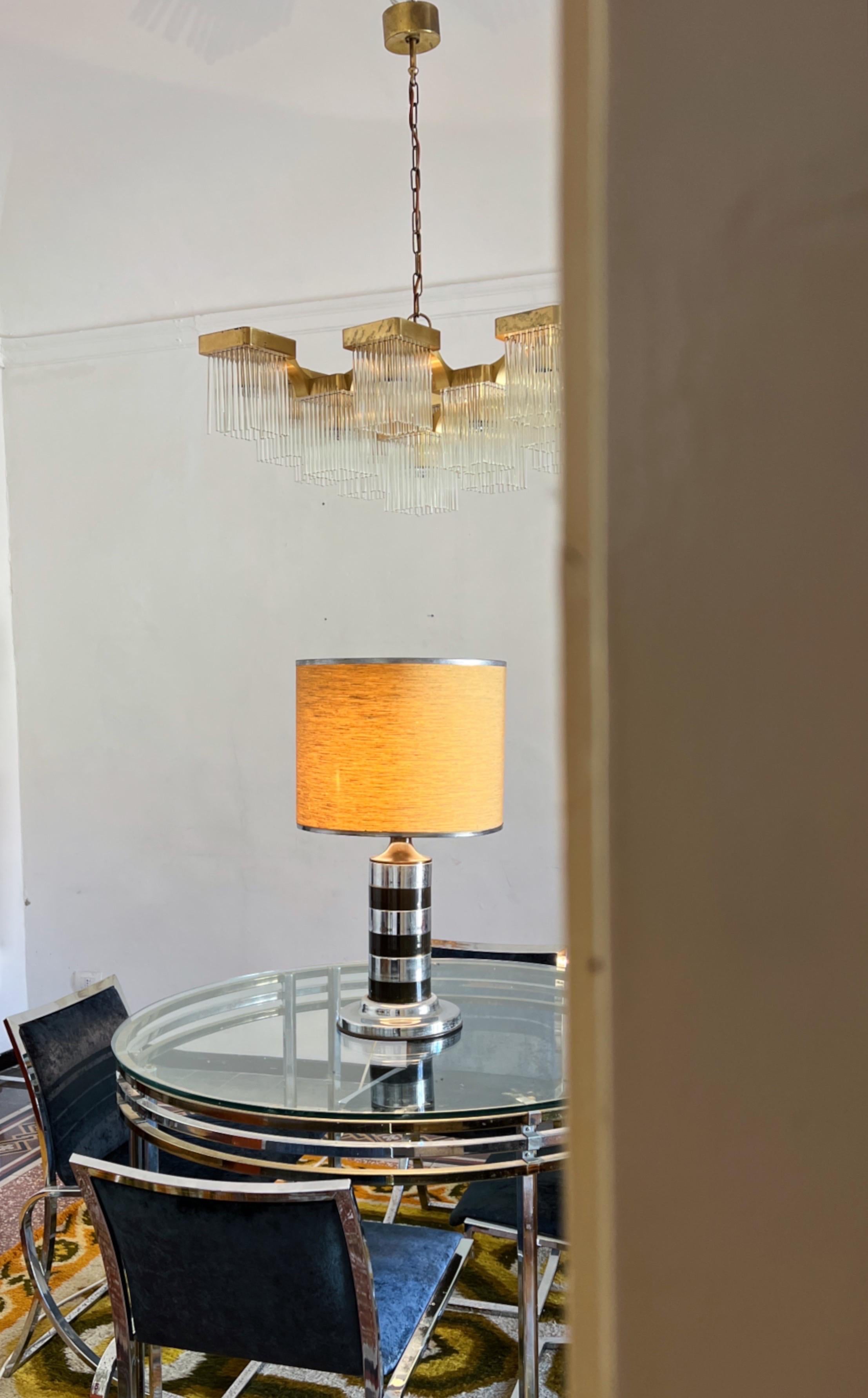 1970s stunning table lamp crafted by the renowned Italian designer, Tommaso Barbi. Its base, adorned with sleek stripes in chromium and brass. Over the years, the brass has developed a charming patina, adding character and depth to its