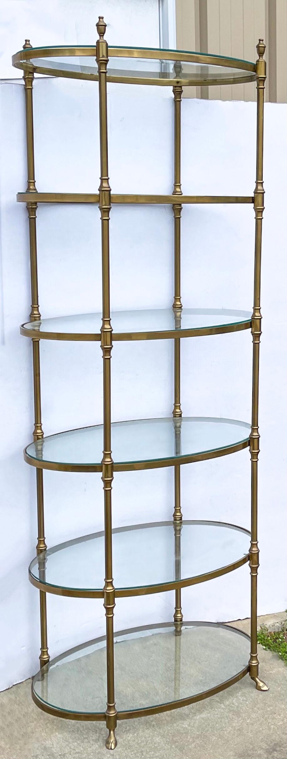 Rare bird! This is a tall 1970s neo-classical Maison Jansen style brass and glass etagere. It is in very good condtion. Note the hoof feet and Doric finials.