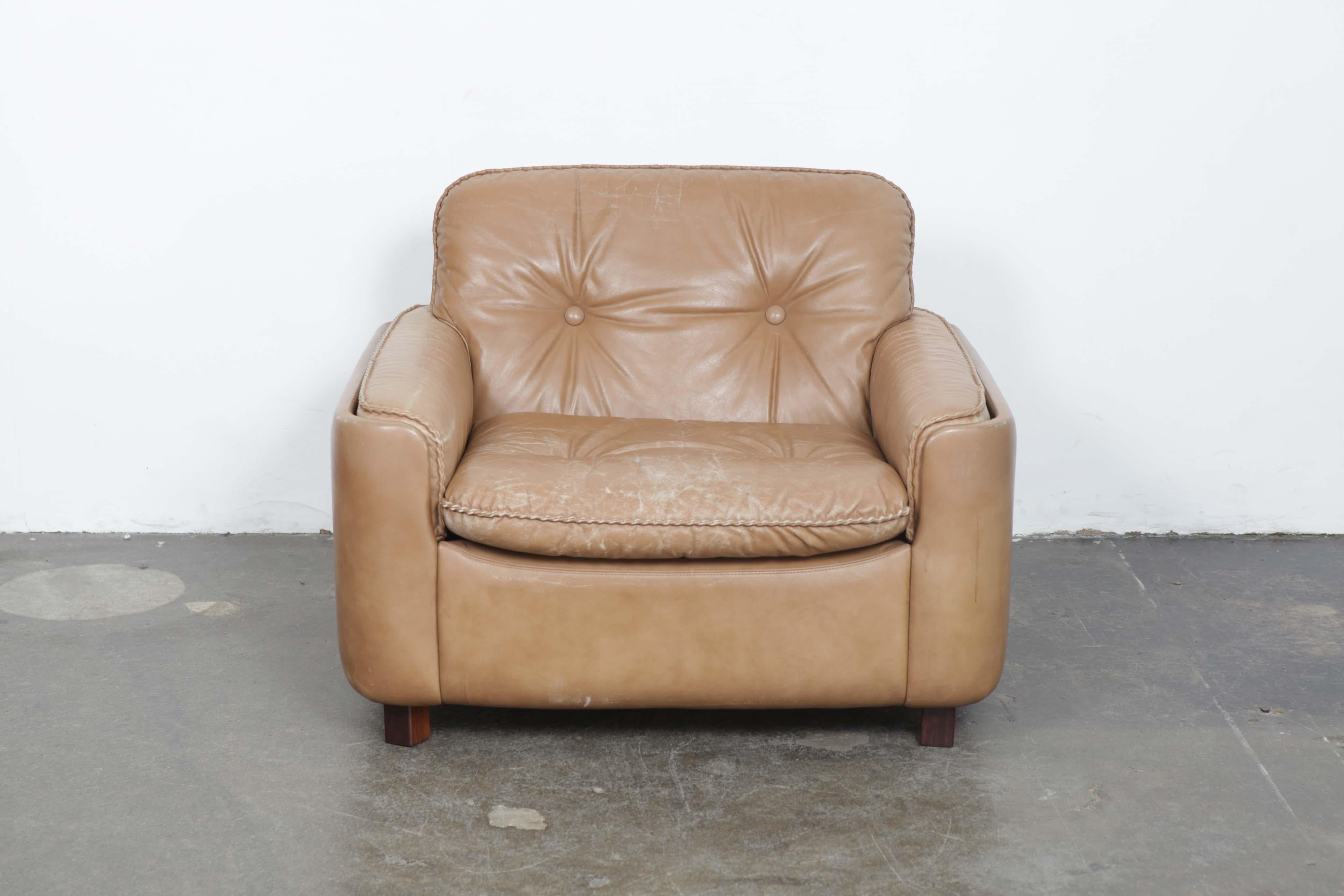 Tan leather low lounge chair designed by Sigurd Ressel produced by Vatne Mobler of Norway, 1960s. Cushions have button tufting as well as baseball stitch seams. Casters in the back and solid wood legs in the front. Patina and wear commensurate with