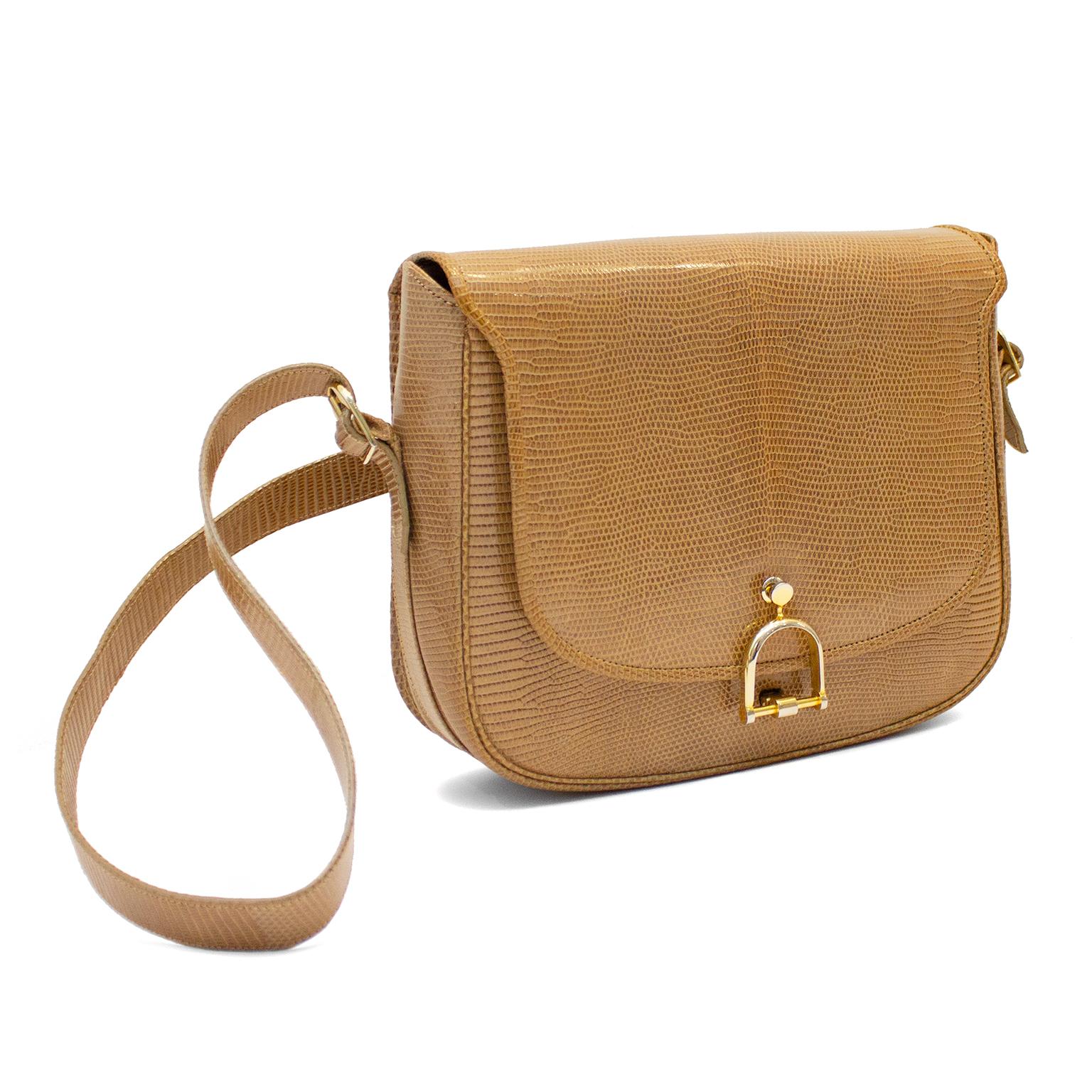 Stunning 1970s tan/taupe embossed skin shoulder bag. Gold tone stirrup detail lock at front. Clean interior. Excellent vintage condition - amazing condition is rare for a bag of this age. Made in Italy for Holt Renfrew Canada. 9